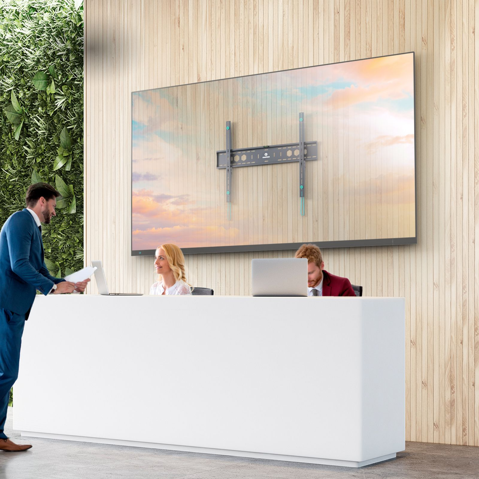 Biuro z recepcją. Ludzie wchodzą w interakcje. Duży ekran, zielona ściana i panele drewniane. Ekran jest zamontowany.