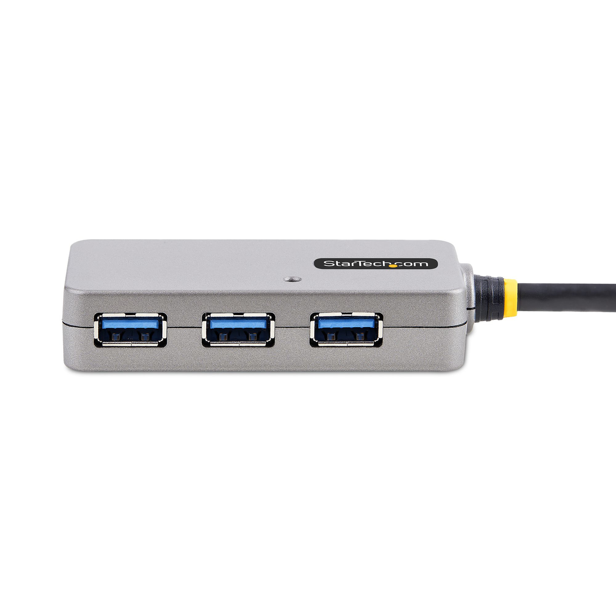 Un concentrador USB plateado con tres puertos. Un cable negro se extiende hacia la derecha. El logotipo de StarTech.com es visible.