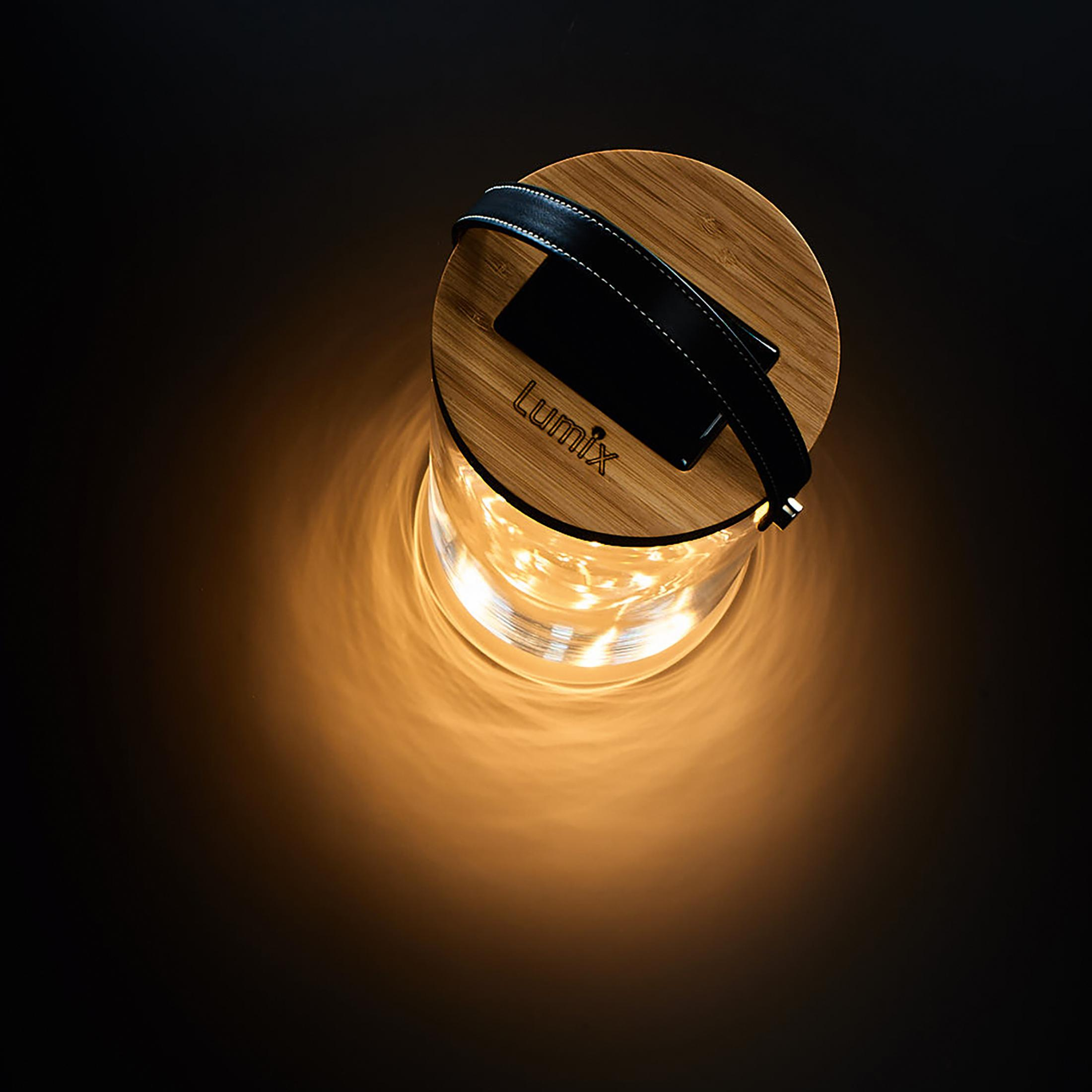 Eine Lumix-Laterne mit Holzdeckel und Ledergriff. Der Glasteil enthält Lichterketten. Sie befindet sich auf dunklem Hintergrund.