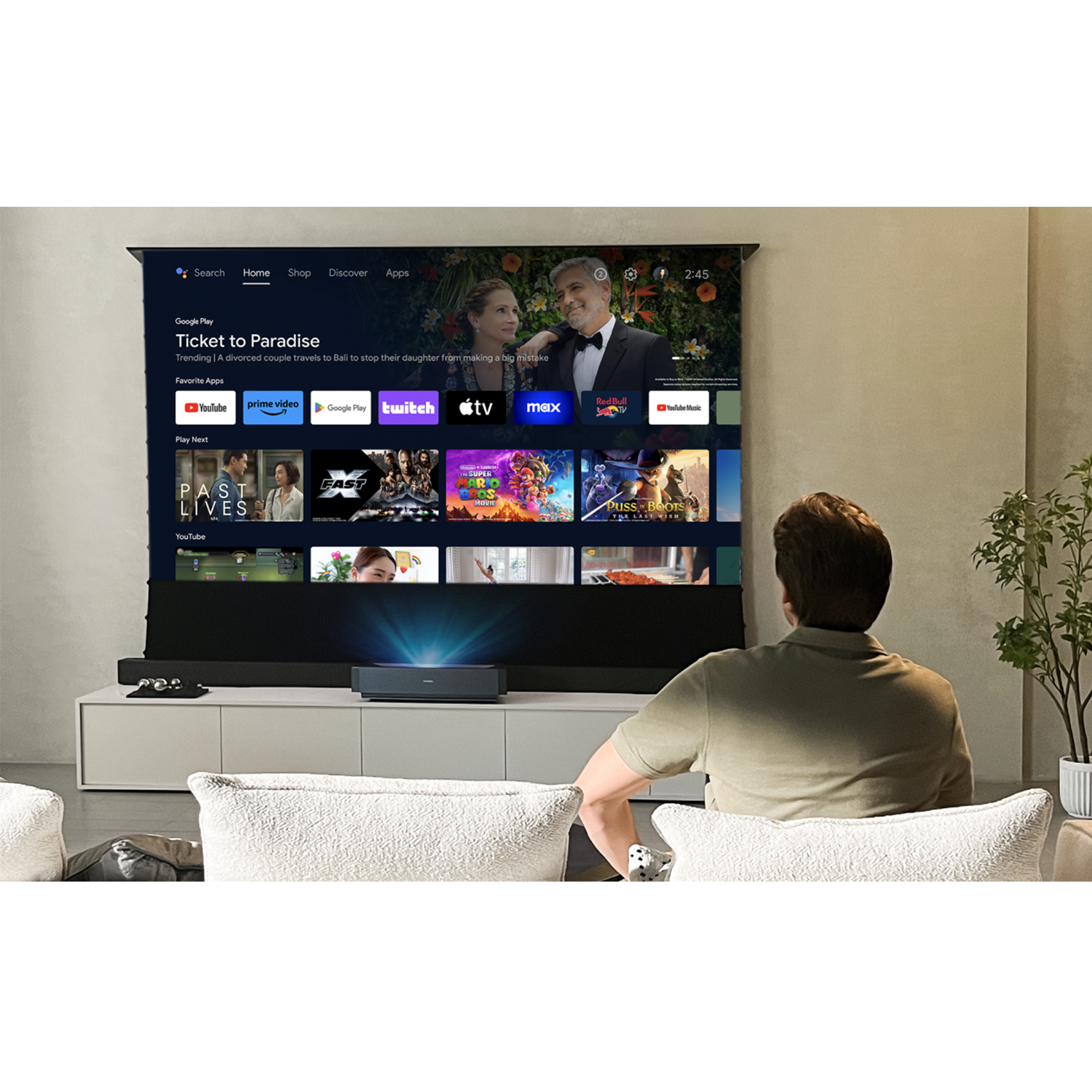 Mężczyzna ogląda film na dużym ekranie, który wyświetla interfejs usługi strumieniowej z tytułami filmów.