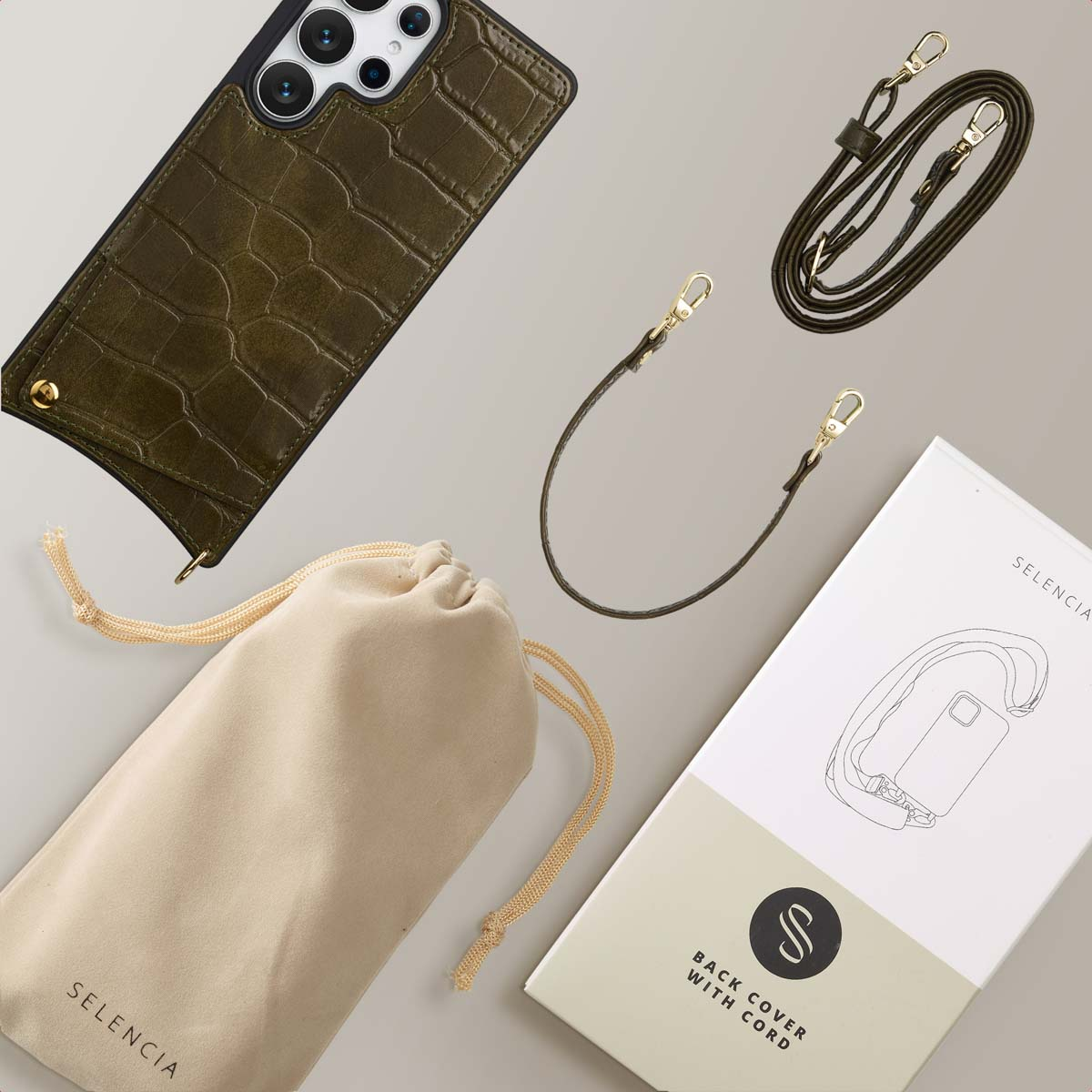 Coque de téléphone vert olive avec sangle et détails dorés, une pochette et une boîte avec une illustration de téléphone sur une surface beige.
