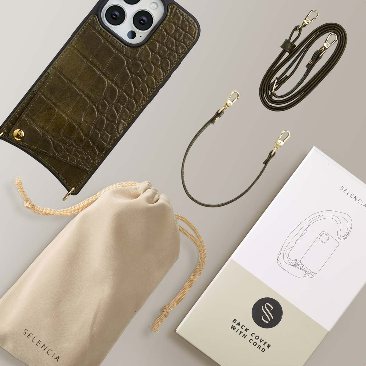 Coque de téléphone vert olive avec sangle et accessoires, une pochette beige, une boîte avec une illustration de téléphone, sur fond gris.
