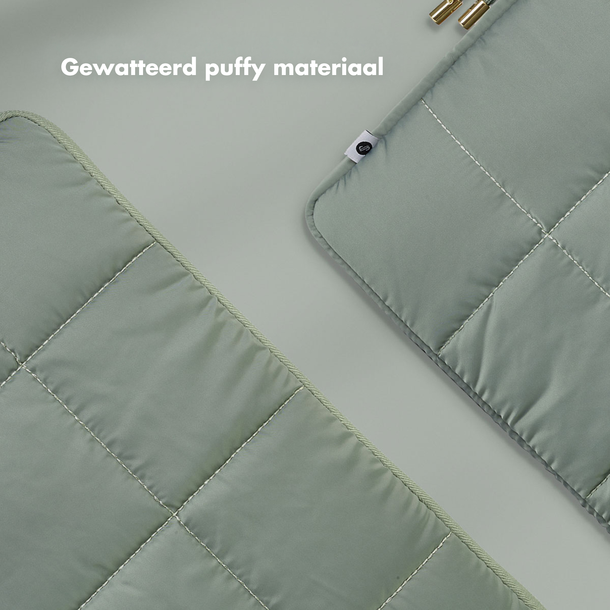 Two quilted, sage-green fabric pieces. One has a label. The background is a light gray. 