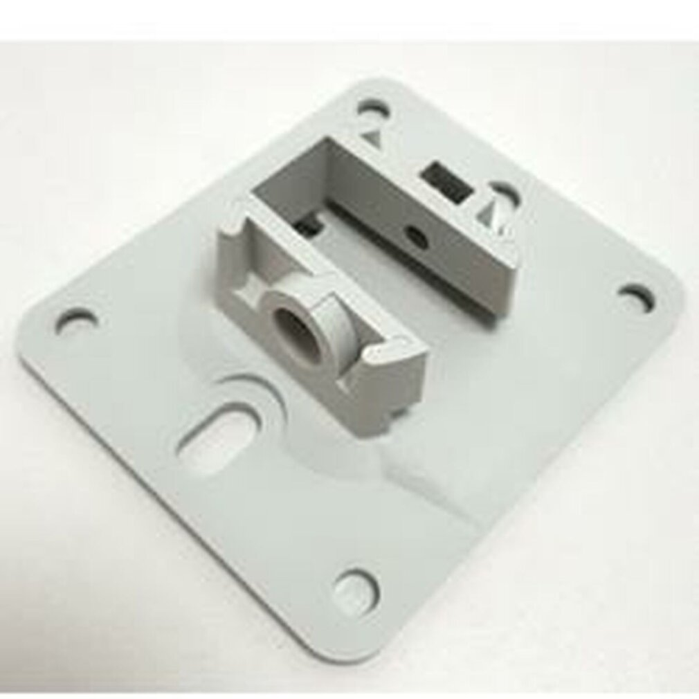 Un soporte de plástico gris con una base rectangular y una sección elevada con un orificio y ranuras. Se ven cuatro agujeros.