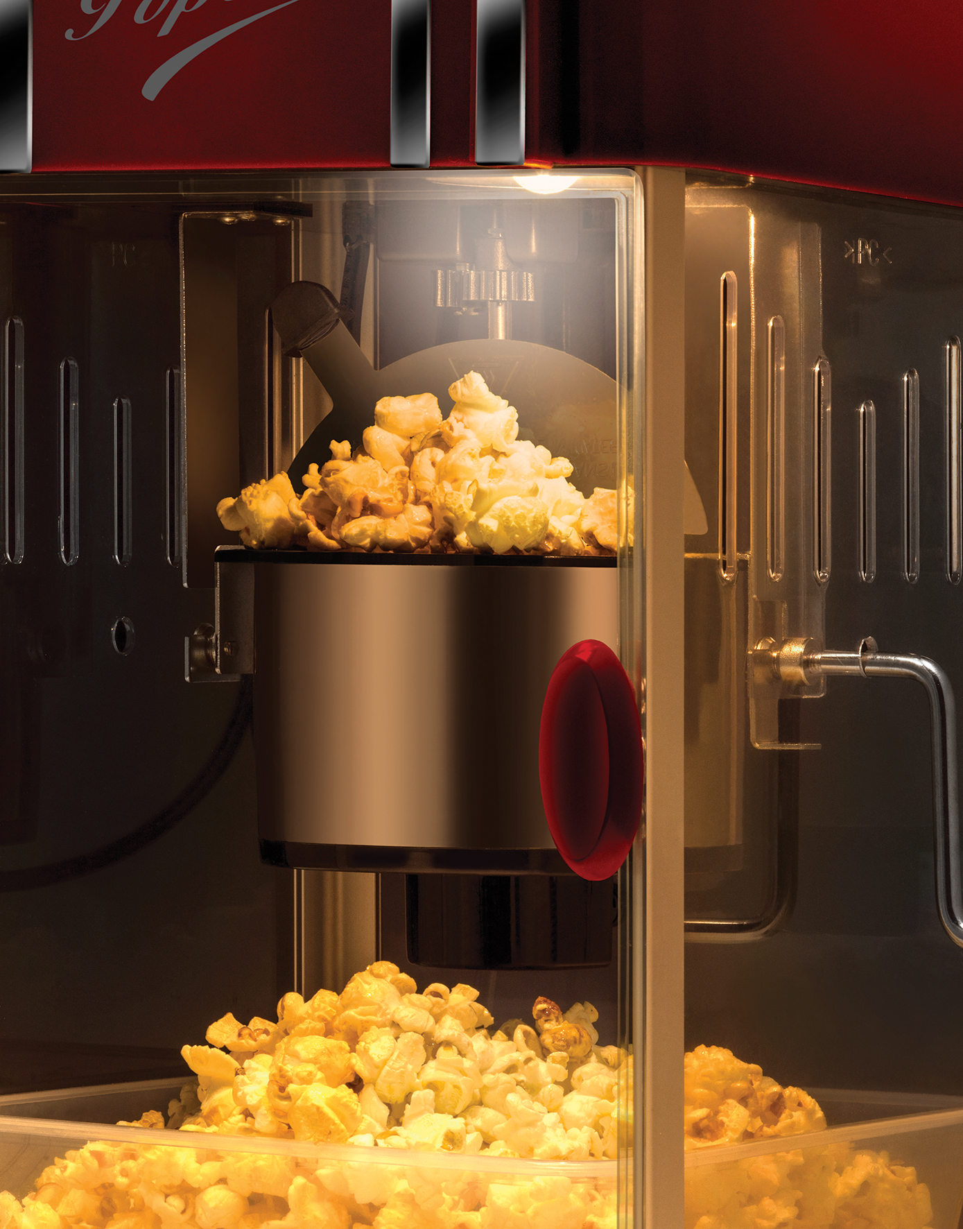 Popcornmaschine mit roten Akzenten. Popcorn befindet sich in der Maschine und in einem darunter liegenden Behälter.