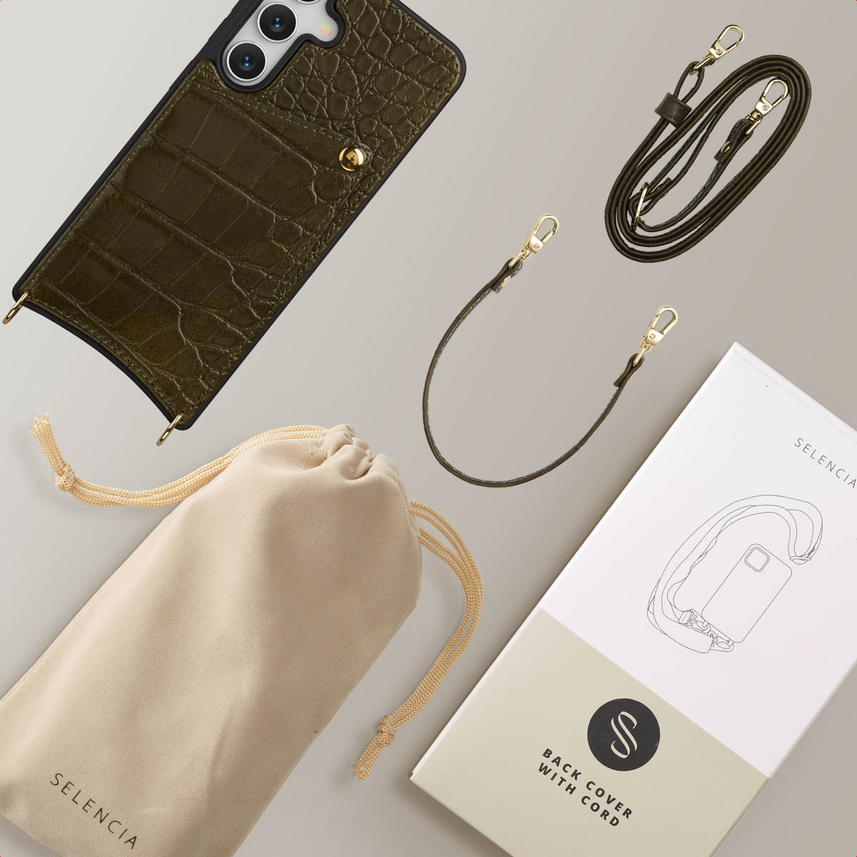 Olijfgroene telefoonhoes met riem en zakje, plus een witte doos. Gouden sluitingen en details. Alles op een neutrale achtergrond.
