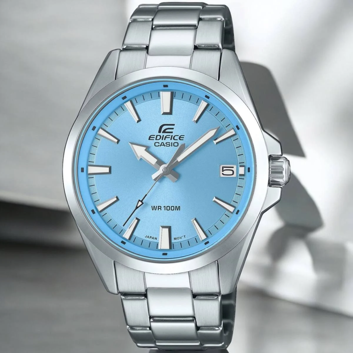 Un reloj plateado Edifice Casio con esfera azul claro, manecillas plateadas y visualización de fecha a las 3.