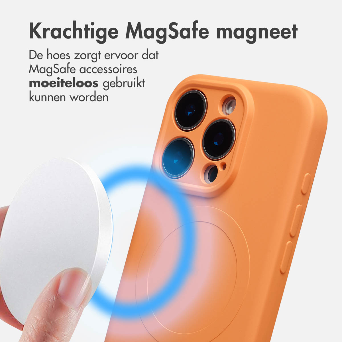 Een oranje telefoonhoesje met een magneet, een witte ronde MagSafe-accessoire en Nederlandse tekst. Een hand houdt de accessoire vast.