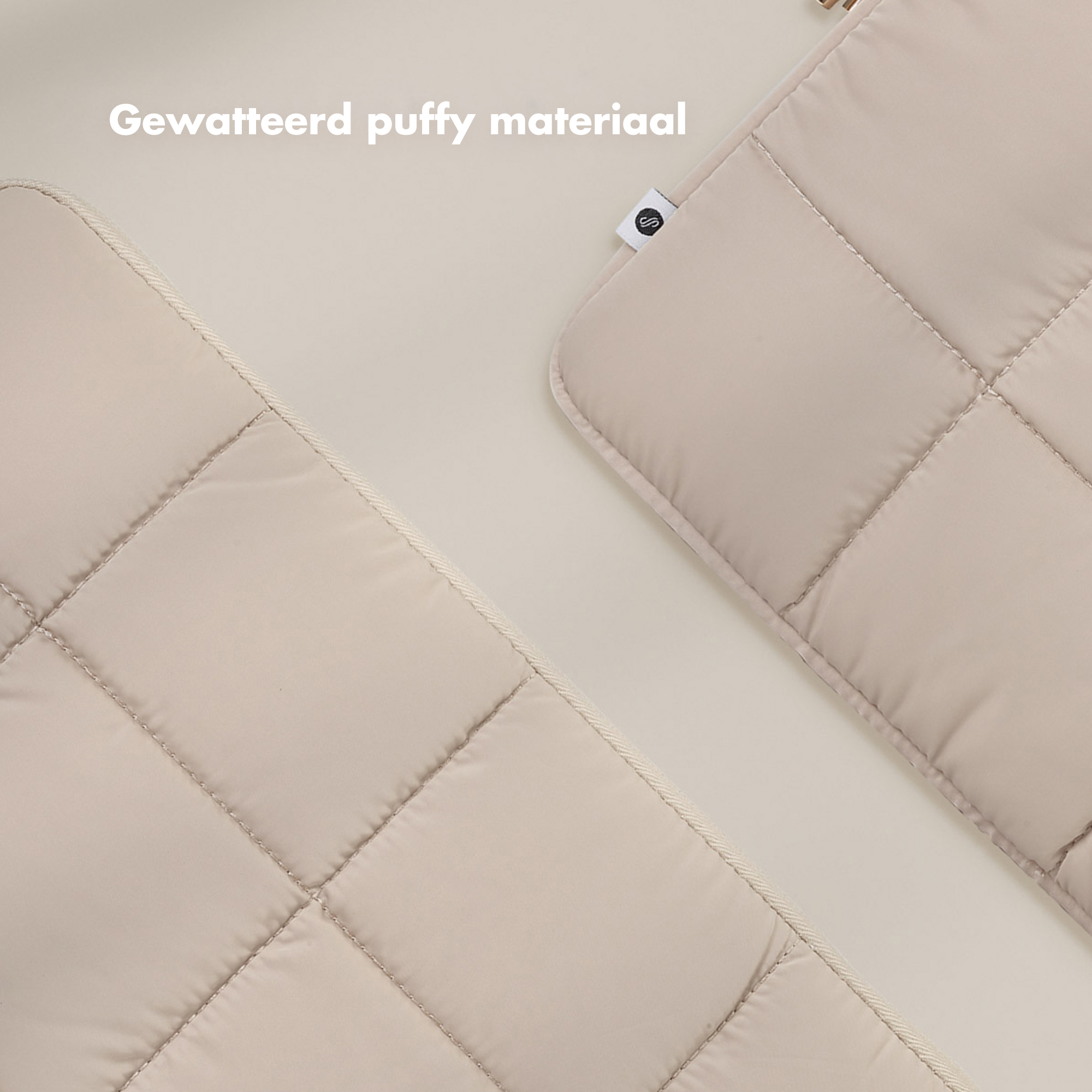 Two beige, quilted fabric pieces diagonally on a light beige background. One has a label.