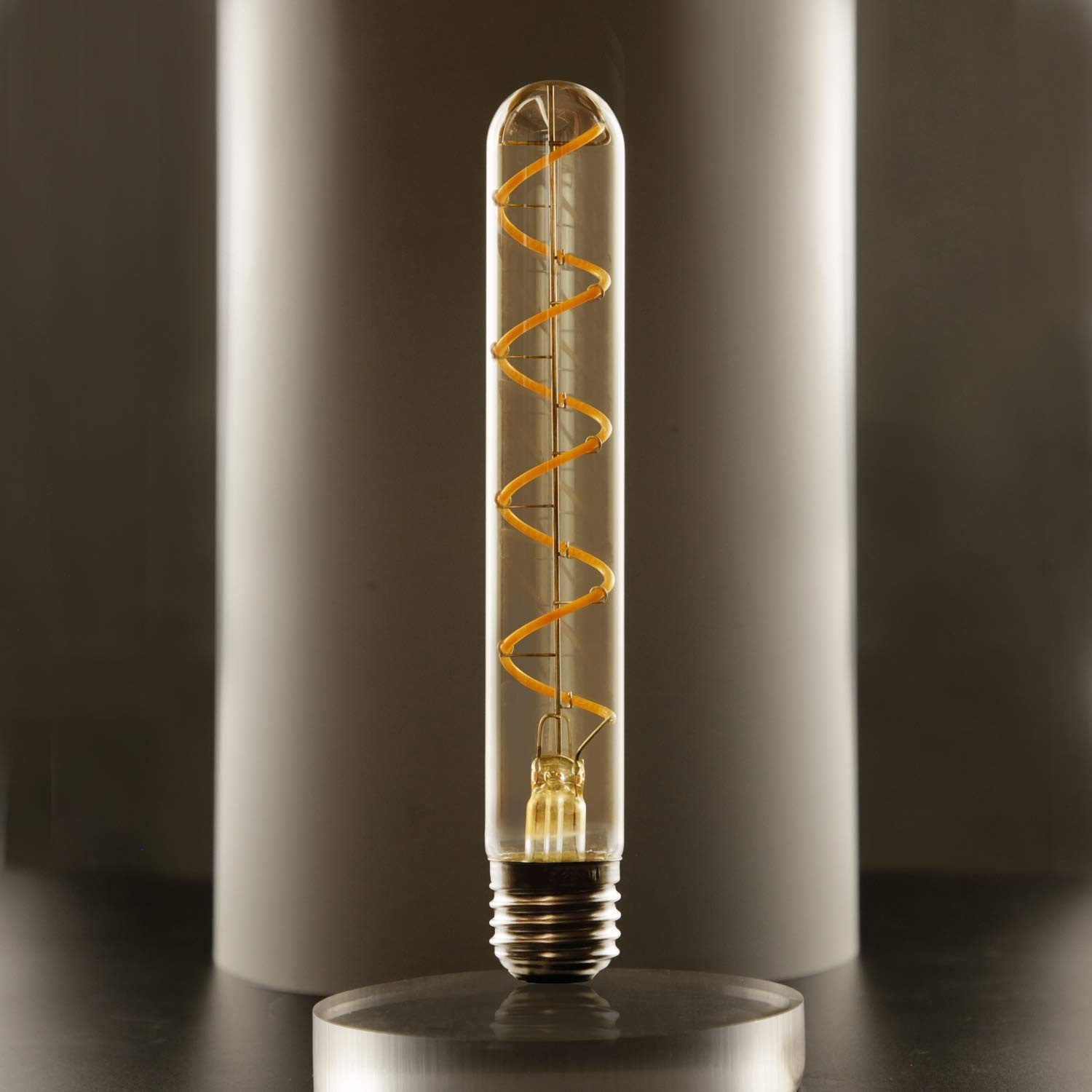 Una lampadina trasparente tubolare con filamento a spirale è su una base cilindrica. Un pilastro bianco sullo sfondo.