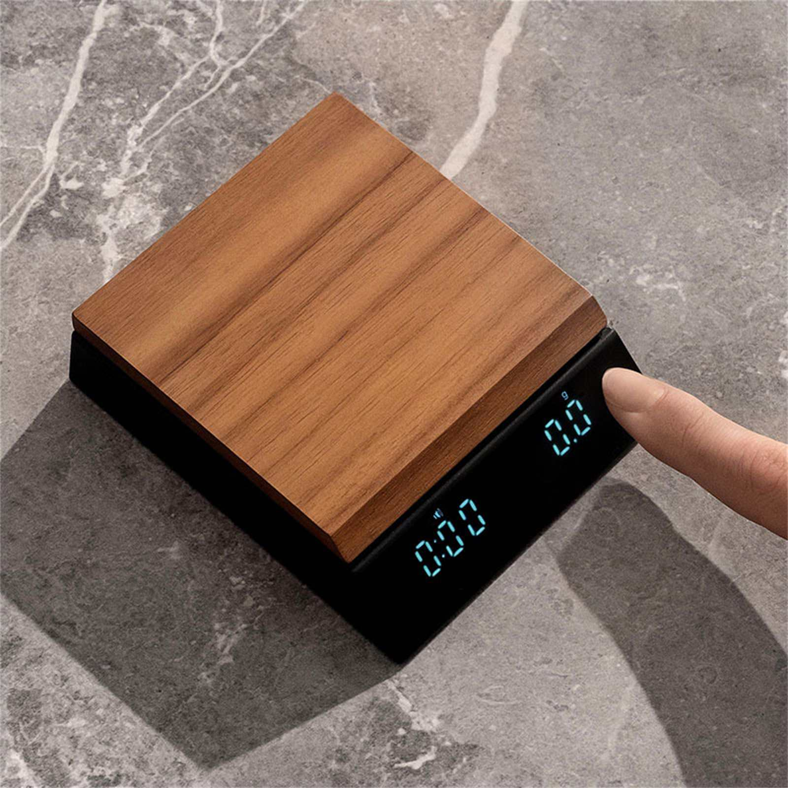 Eine digitale Küchenwaage mit Holzplatte liegt auf Marmor. Ein Finger berührt das Display der Waage.