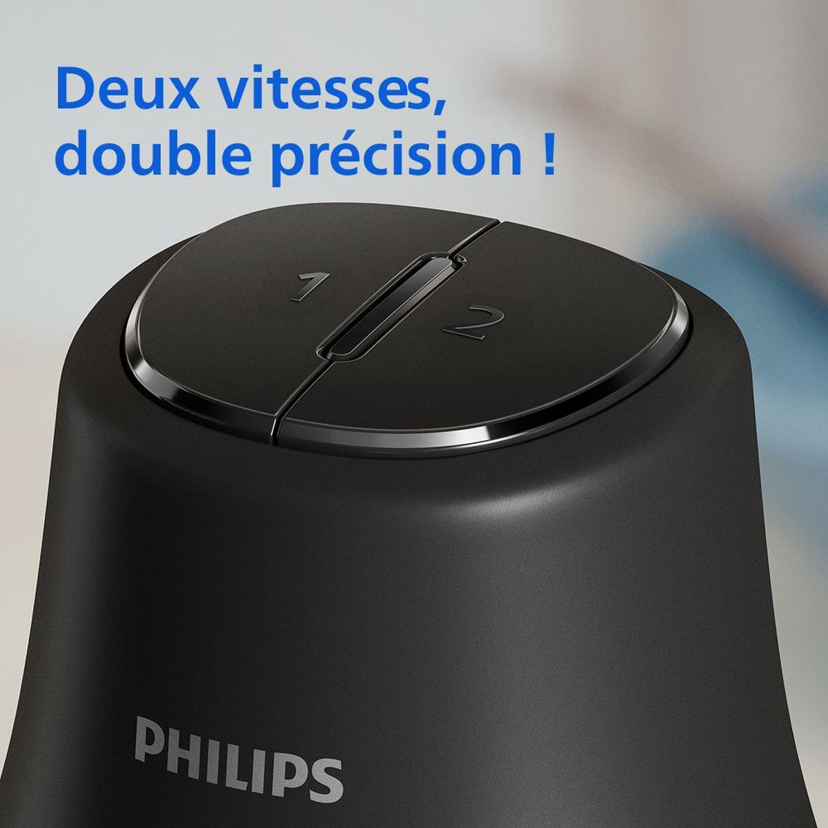 Nahaufnahme eines schwarzen Philips-Geräts. Es hat eine runde Oberseite mit den Geschwindigkeitseinstellungen 1 und 2. Der Text 'Deux vitesses, double précision!' steht darüber.