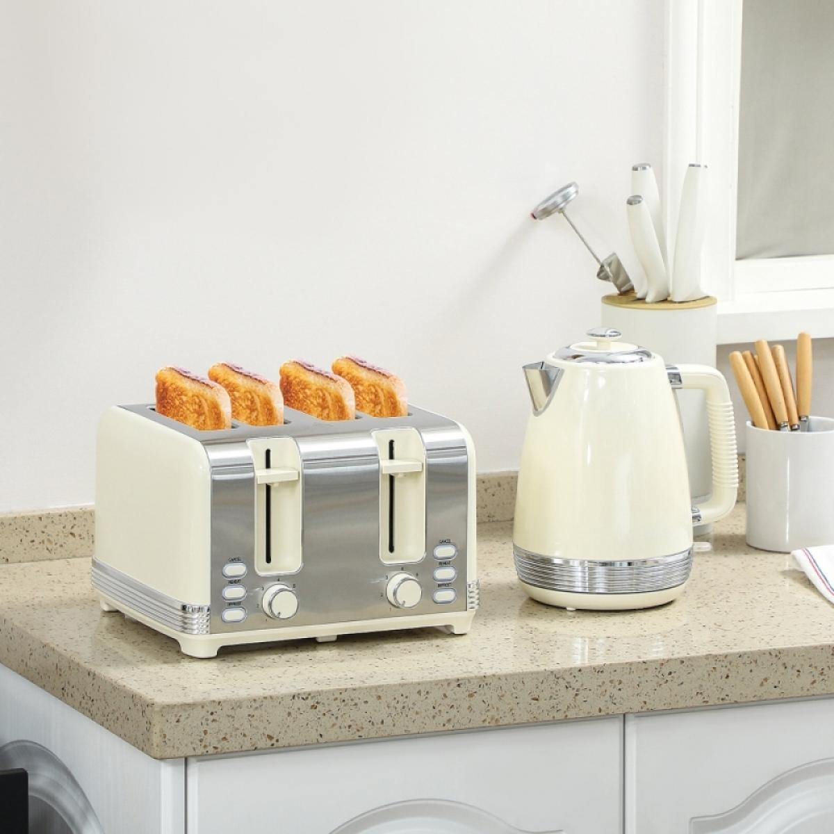 Ein cremefarbener und silberner Toaster mit vier Toastscheiben, ein Wasserkocher, Messer und Utensilien auf einer Küchenarbeitsplatte.