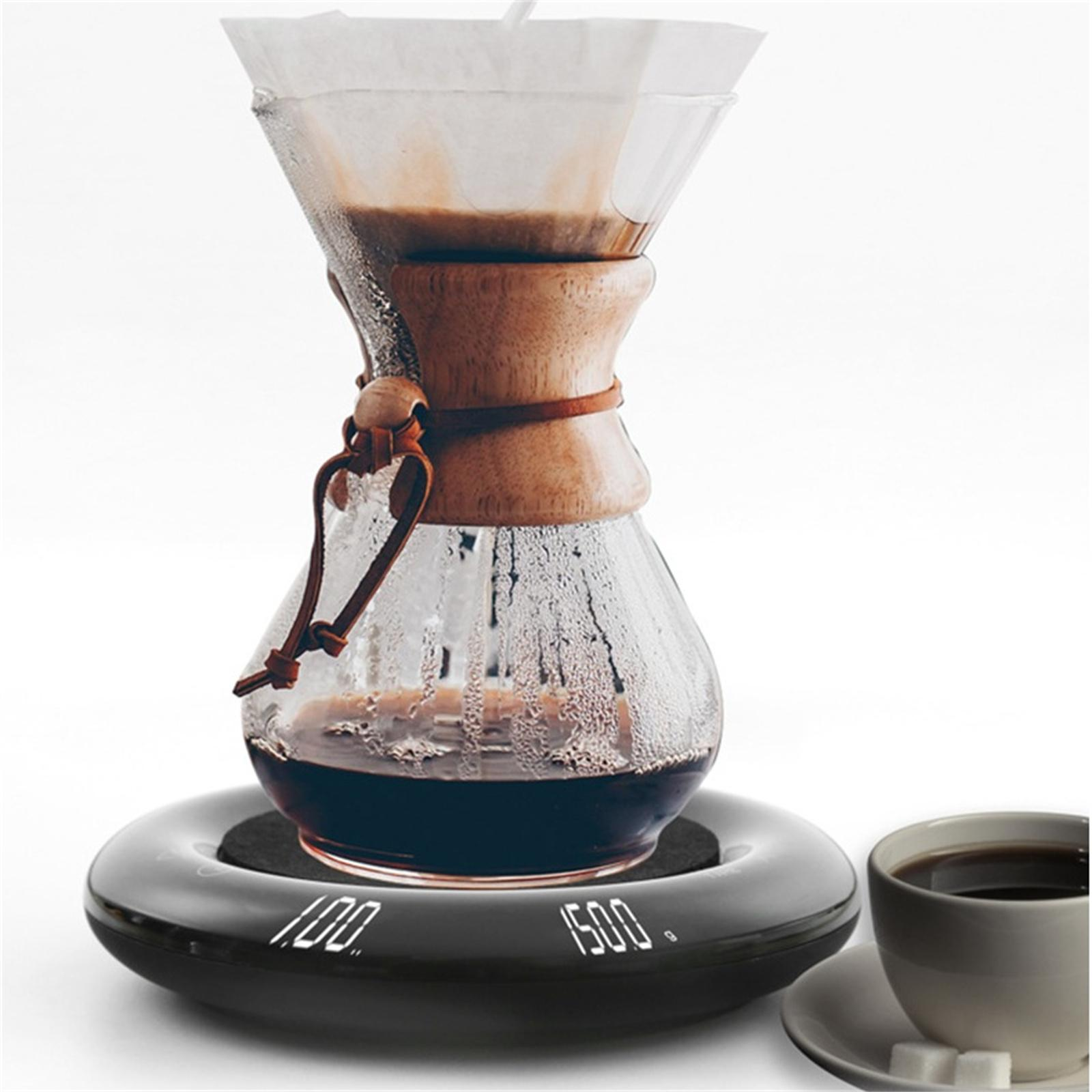 Kaffee wird in einer Glaskaraffe auf einer Waage gebrüht. Eine Tasse Kaffee und Würfelzucker sind in der Nähe.