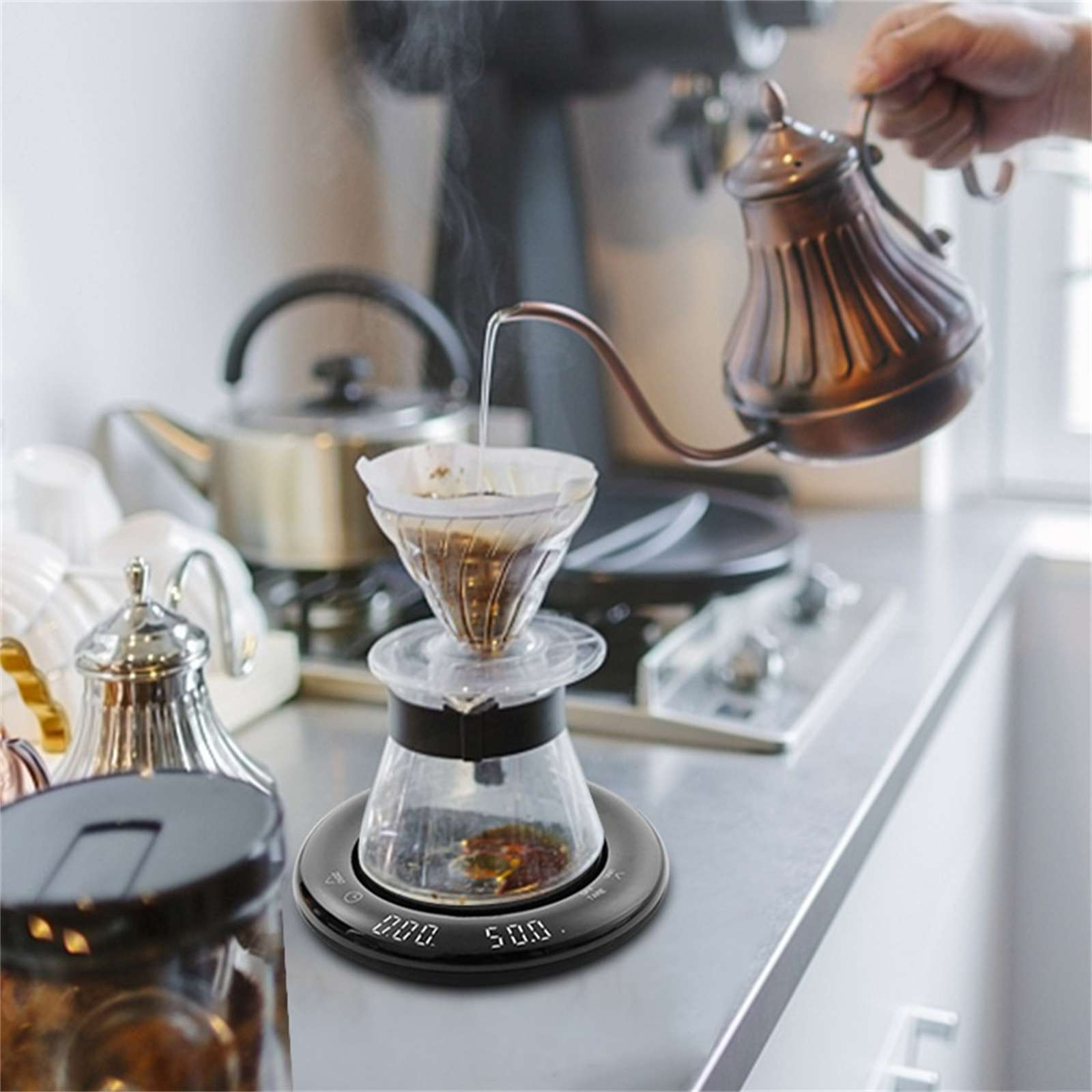 Eine Person gießt heißes Wasser aus einem Kupferkessel in einen Kaffeefilter. Eine Waage zeigt Zeit und Gewicht an.