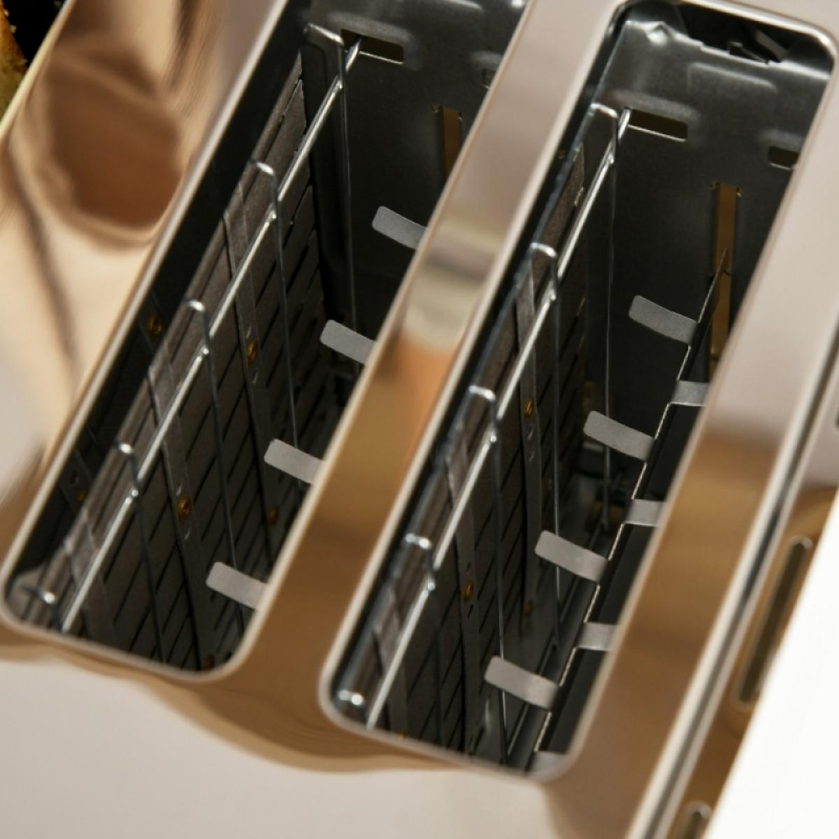 Nahaufnahme eines Toasters aus Edelstahl. Zwei Schlitze sind sichtbar, mit internen Metallkomponenten. Der Toaster hat eine glänzende, reflektierende Oberfläche.