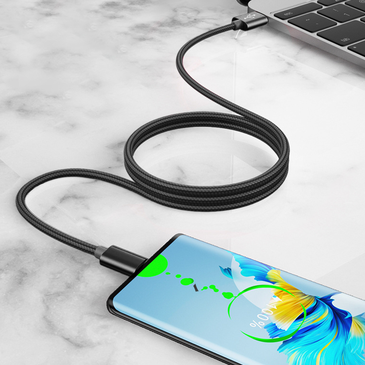 Ein Telefon, das mit einem schwarzen Kabel geladen wird. Das Telefon zeigt eine Ladeanzeige. Im Hintergrund ist auch ein Laptop zu sehen.