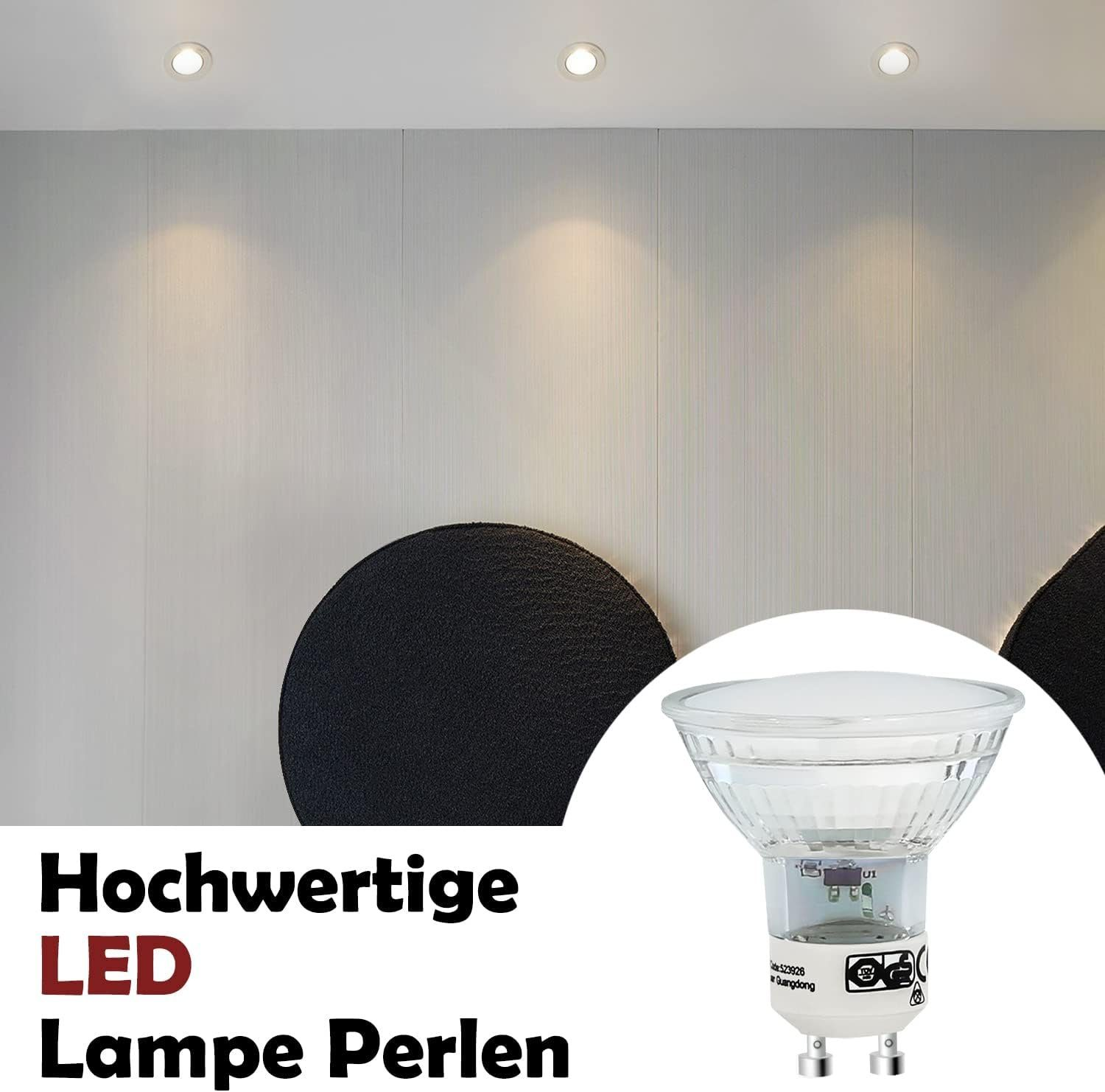 Primo piano di una lampada LED con vetro trasparente e base bianca. Lo sfondo mostra un muro bianco e tre luci a soffitto.
