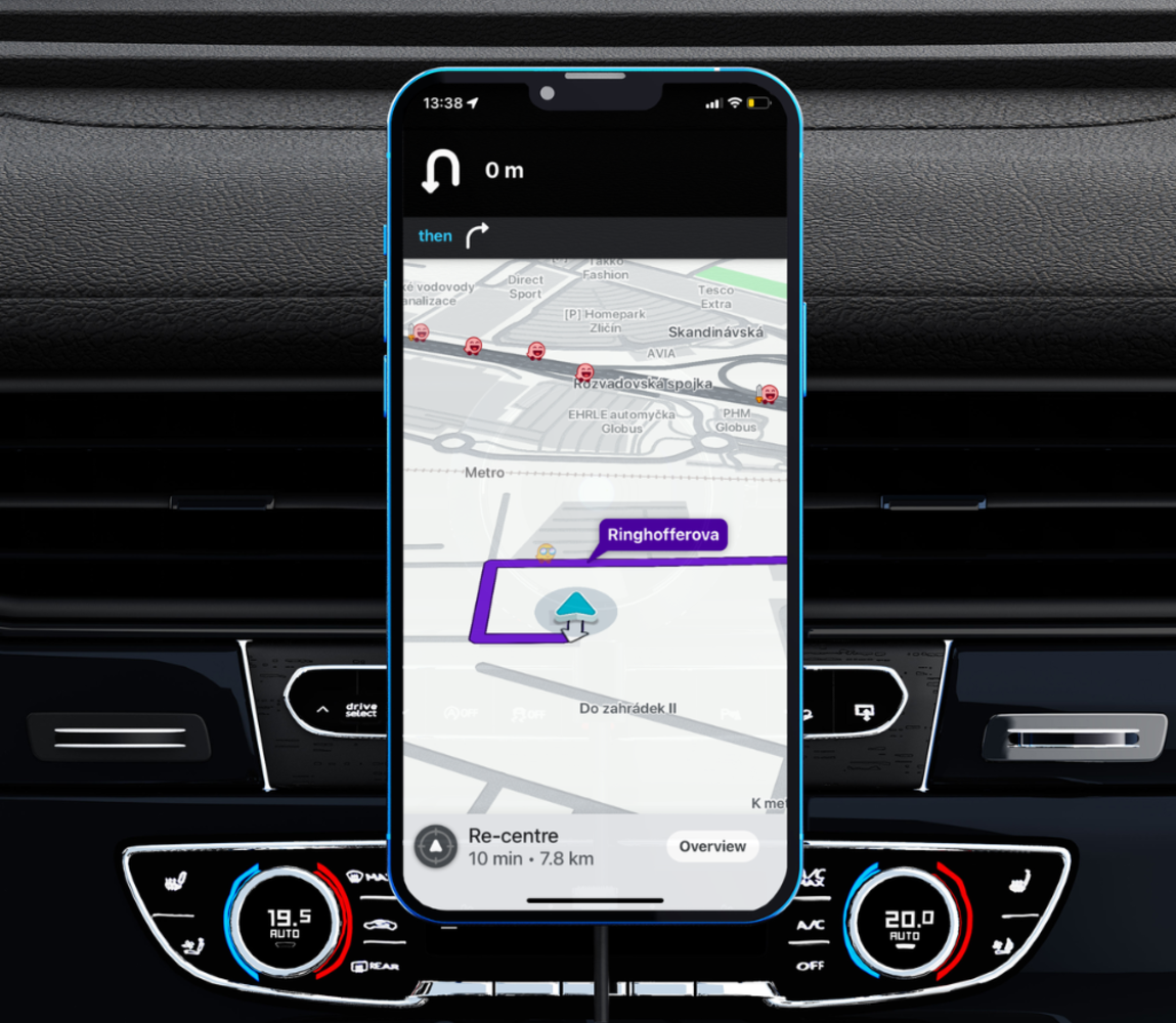Uno smartphone mostra un'app di navigazione con un percorso su una mappa. Il telefono è sul cruscotto di un'auto. Lo schermo mostra Ringhofferova.