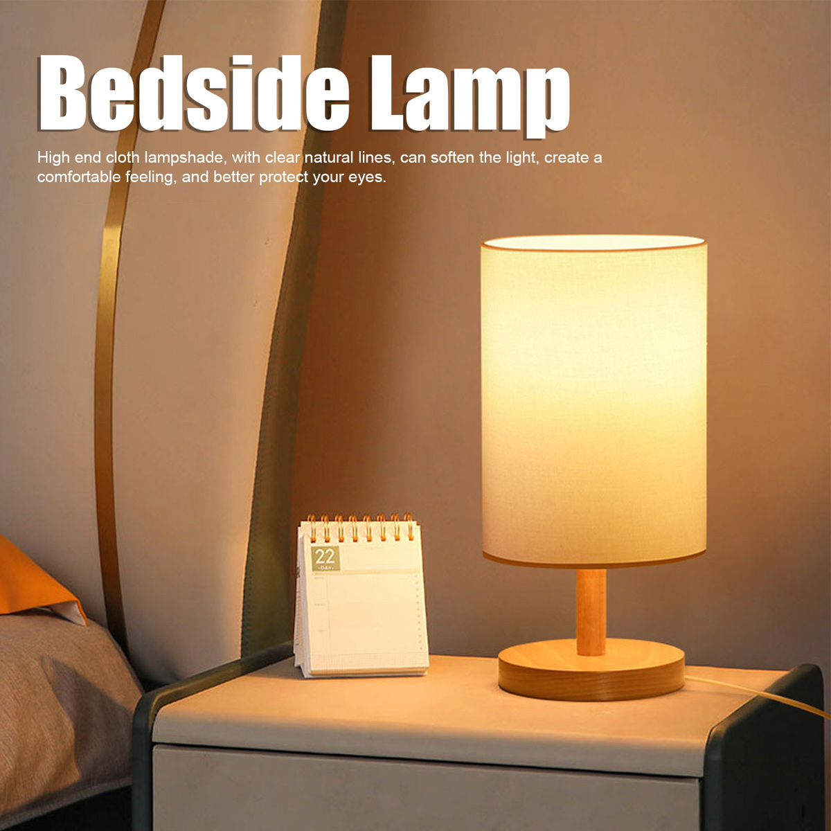 Eine beleuchtete Nachttischlampe auf einem Nachttisch. Ein Kalender ist in der Nähe. Im Hintergrund eine Wand und ein Bett.