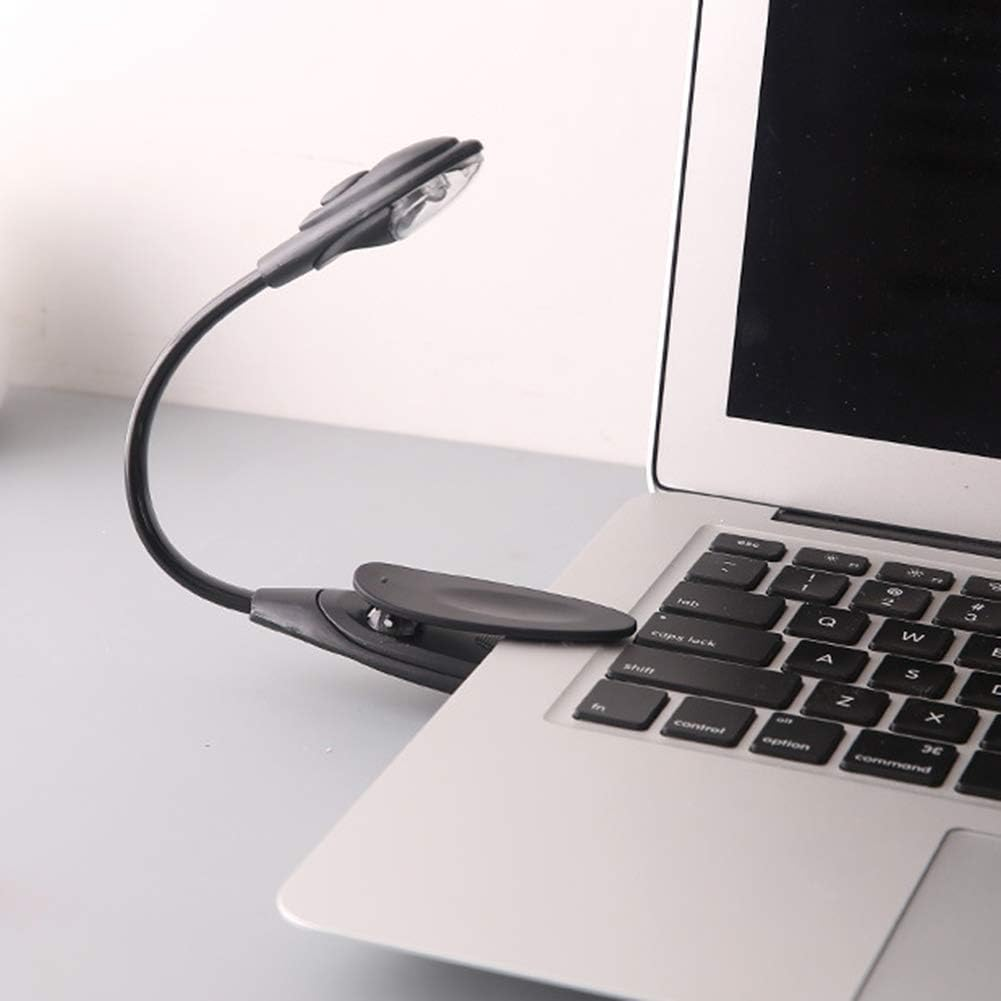 Eine schwarze LED-Clip-On-Lampe an einem Laptop befestigt. Der Laptop ist geöffnet und zeigt die Tastatur. Die Lampe befindet sich über der Tastatur.