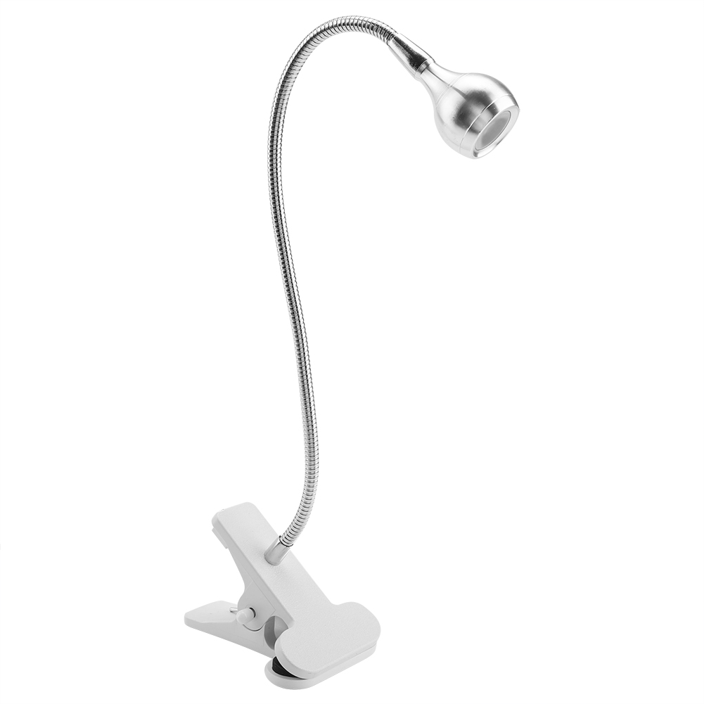 Eine silberne Schreibtischlampe mit flexiblem Hals und weißem Clipfuß, isoliert auf weißem Hintergrund.