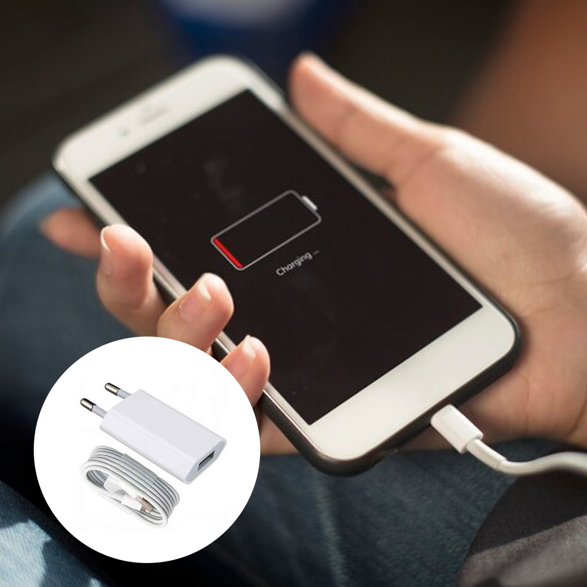 Eine Hand, die ein Telefon hält, das geladen wird. Das Telefon zeigt ein Symbol für schwache Batterie. Ladegerät und Kabel sind links.
