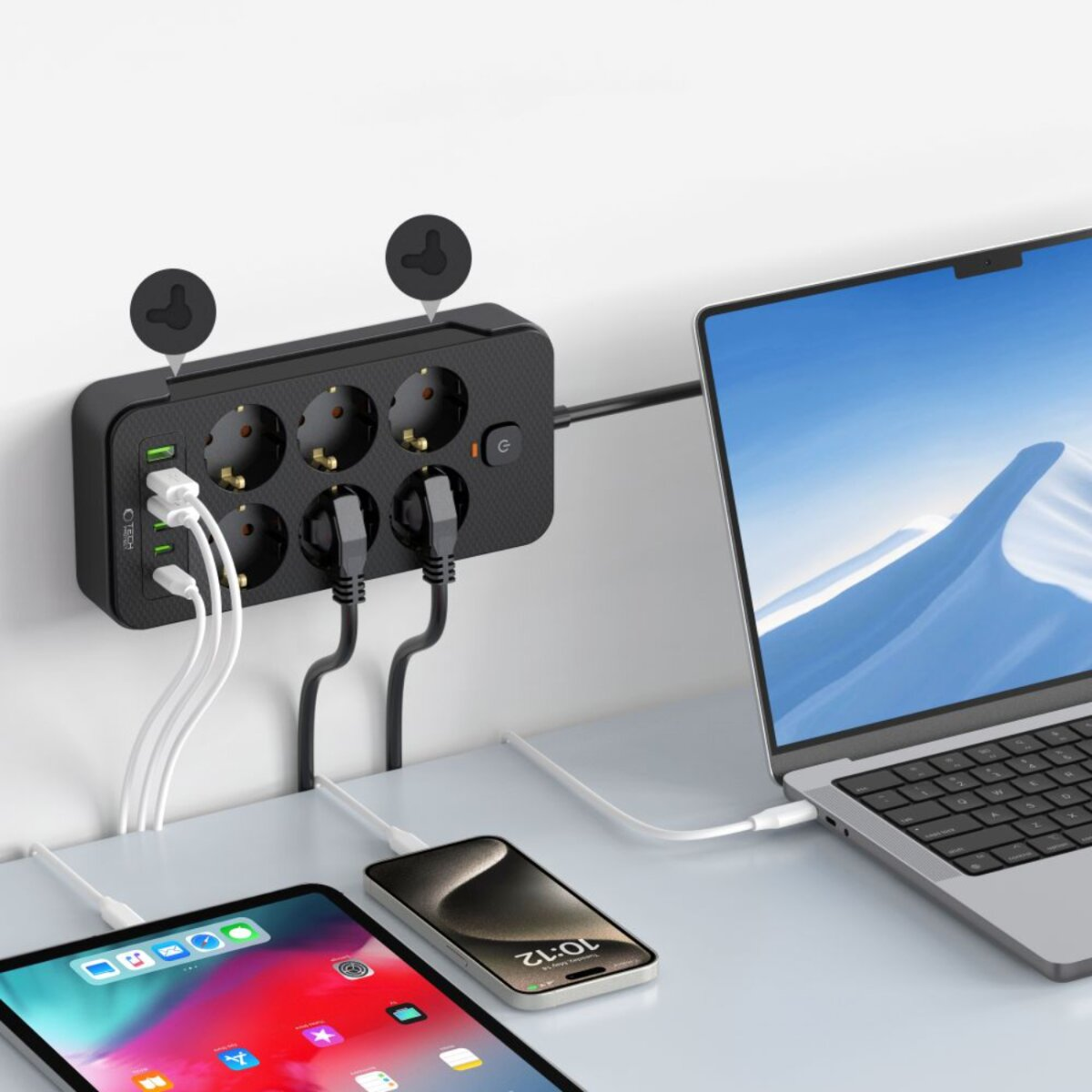 A power strip with sockets and USB ports. Connected to a laptop, phone, and tablet. White and black cables are visible.