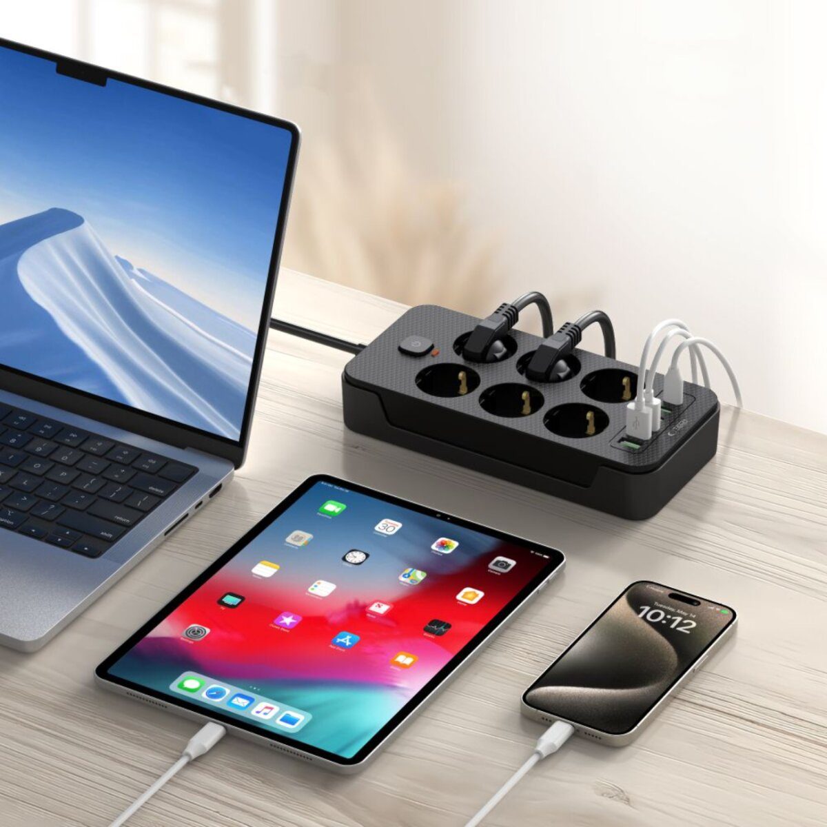 A laptop, tablet, and phone are charging on a wooden table. A black power strip with multiple outlets is also present.