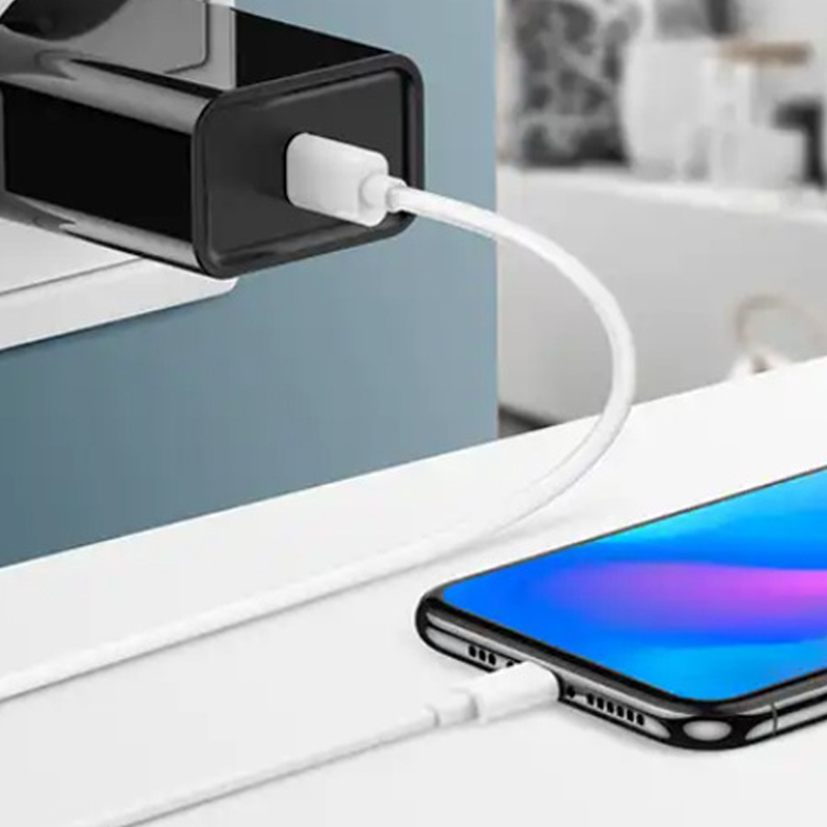 Ein Telefon wird mit einem weißen Kabel aufgeladen. Ein schwarzes Ladegerät ist an der Wand angeschlossen. Das Telefon hat einen blau-violetten Bildschirm.