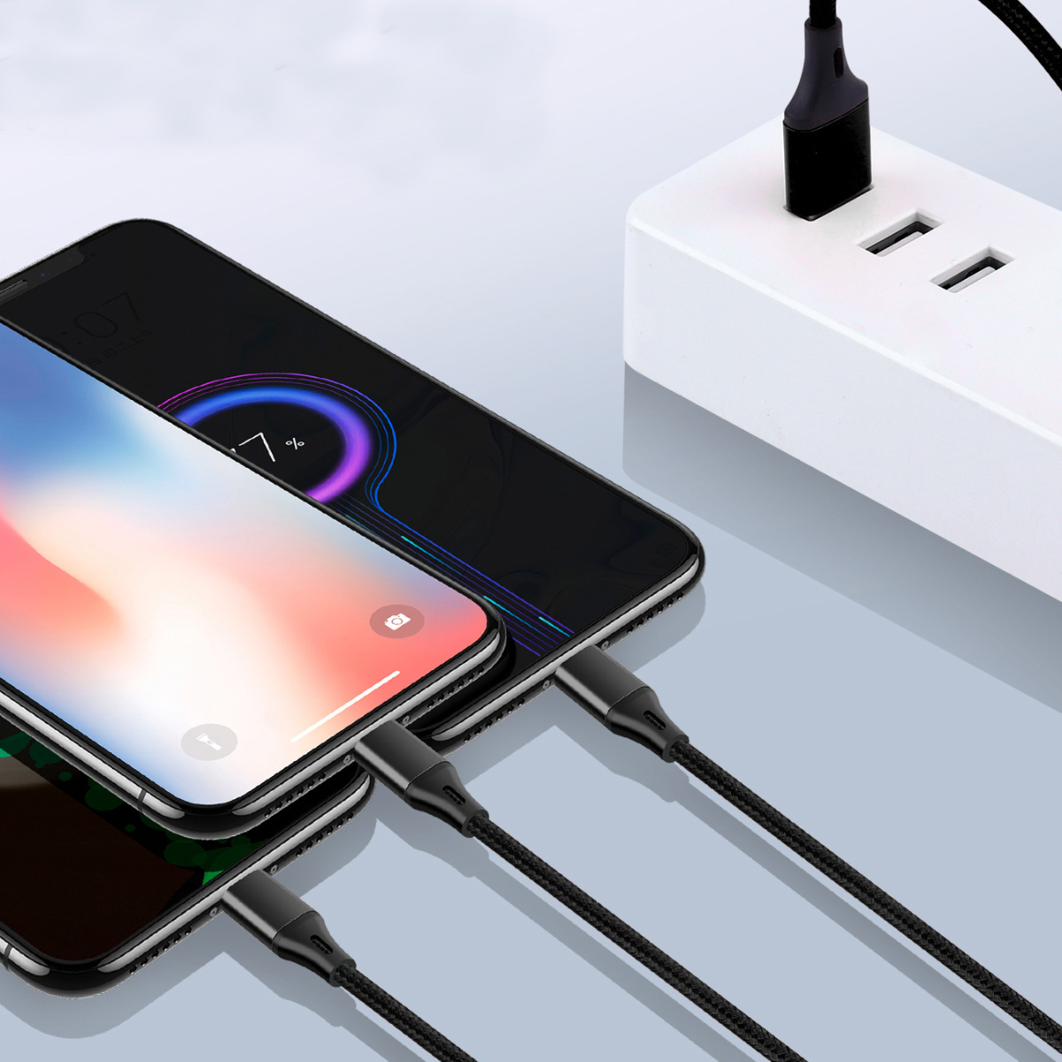 Drei Smartphones laden über schwarze Kabel, die mit einer weißen Steckdosenleiste verbunden sind. Zwei Telefone zeigen Ladebildschirme.