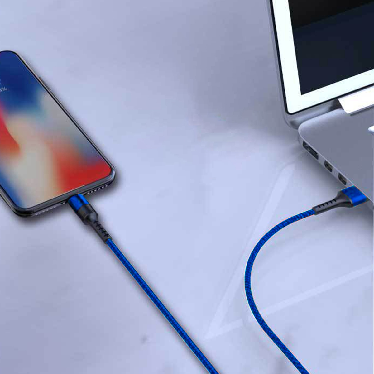 Ein Telefon wird mit einem blauen Kabel aufgeladen, das mit einem Laptop verbunden ist. Der Telefonbildschirm zeigt ein farbenfrohes Bild.