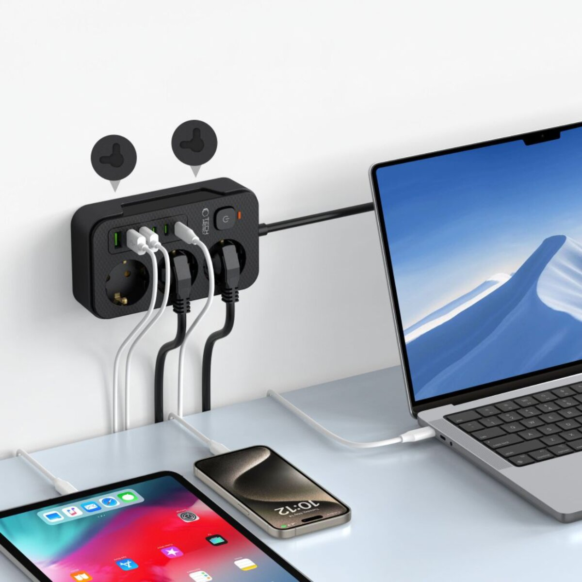 Multiprise noire avec plusieurs appareils branchés. Un ordinateur portable, une tablette et un téléphone sont également en charge.