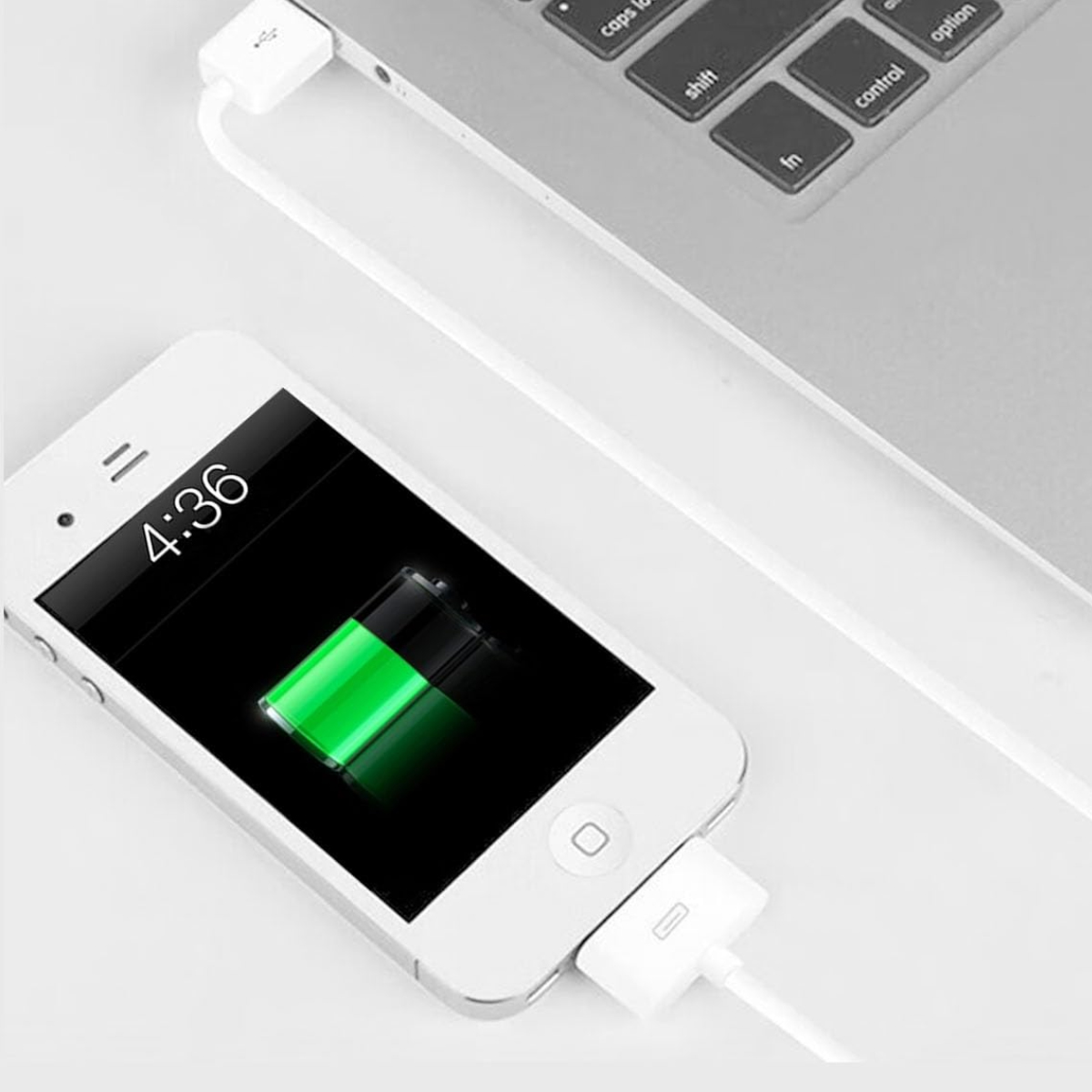 Ein weißes iPhone lädt. Der Bildschirm zeigt 4:36 und ein Batteriesymbol. Ein weißes Kabel verbindet es mit einem Laptop.