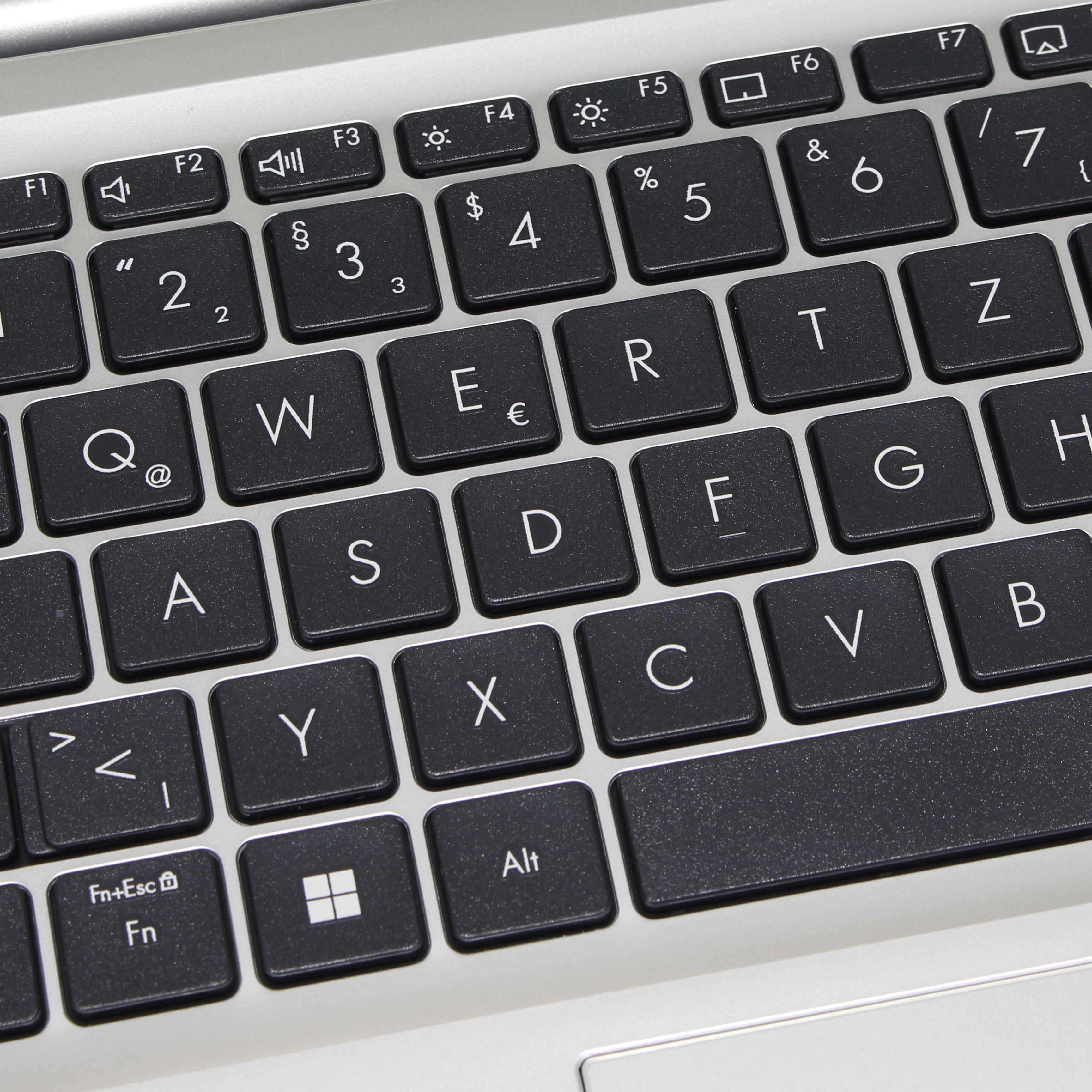 Primer plano de un teclado de portátil con teclas negras y letras blancas. Las teclas incluyen letras, números y símbolos.