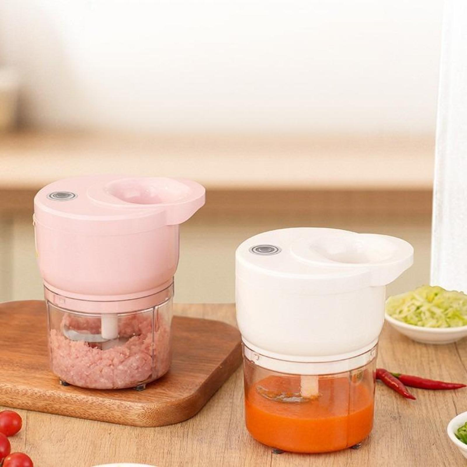 Zwei elektrische Zerkleinerer, einer rosa mit Hackfleisch, einer weiß mit Orangensauce. Gemüse daneben.