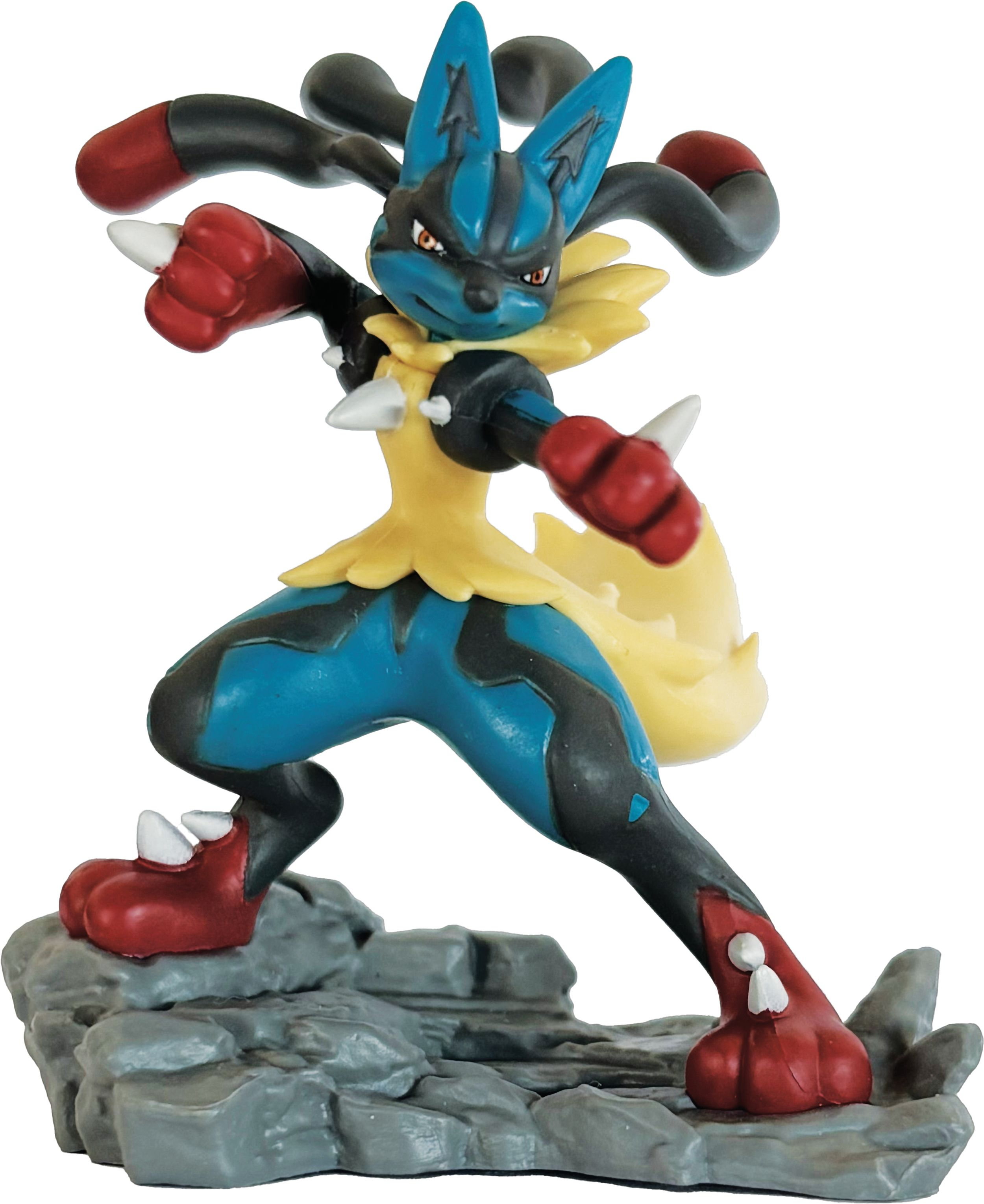 Eine Lucario-Figur steht auf einem Felsensockel. Sie ist blau, gelb und schwarz. Sie befindet sich in einer Kampfhaltung mit roten Akzenten.