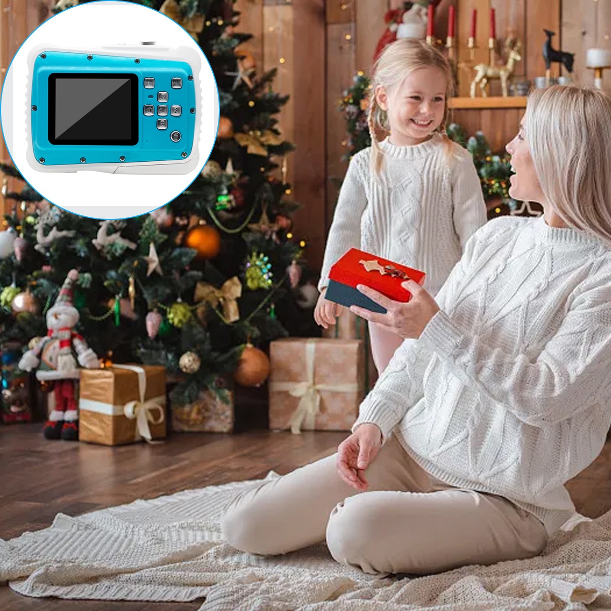 Eine Frau und ein Mädchen stehen vor einem Weihnachtsbaum. Die Frau hält ein Geschenk. Eine Kamera ist oben links.