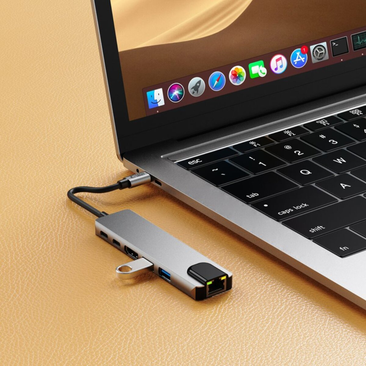 Een laptop met een zilveren USB-hub is aangesloten. Het scherm toont een bureaublad met app-iconen. Het toetsenbord is zichtbaar.