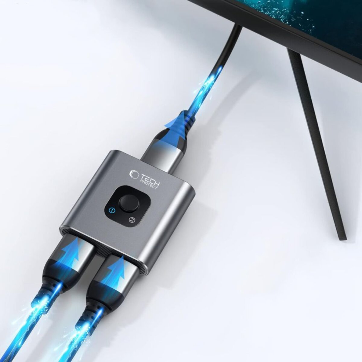 Een grijze Tech Protect-apparaat met kabels en pijlen omhoog, aangesloten op een monitor. De achtergrond is wit.