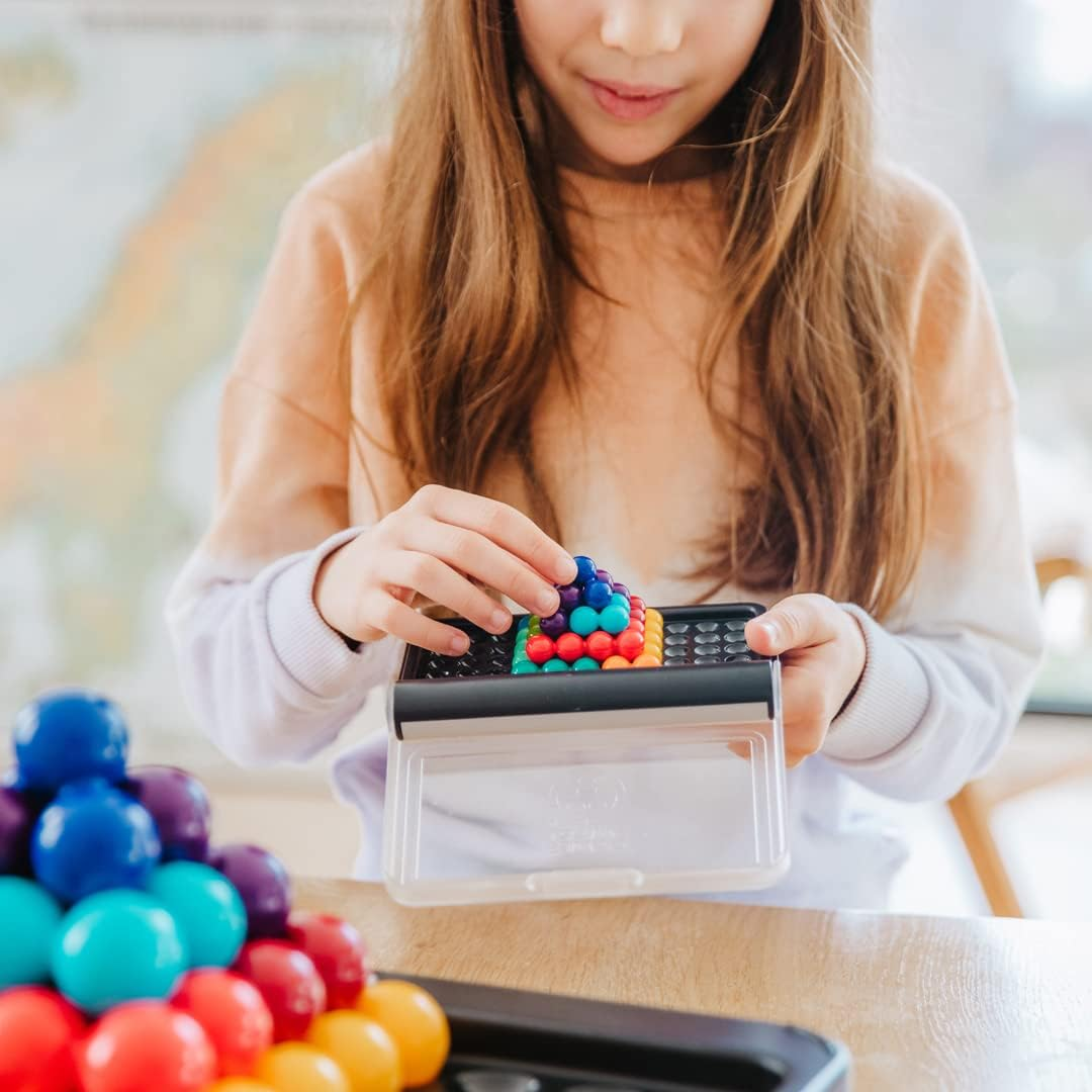 Ein Mädchen spielt mit bunten Magnetkugeln. Sie hält eine Schale mit einer pyramidenförmigen Struktur von Kugeln.