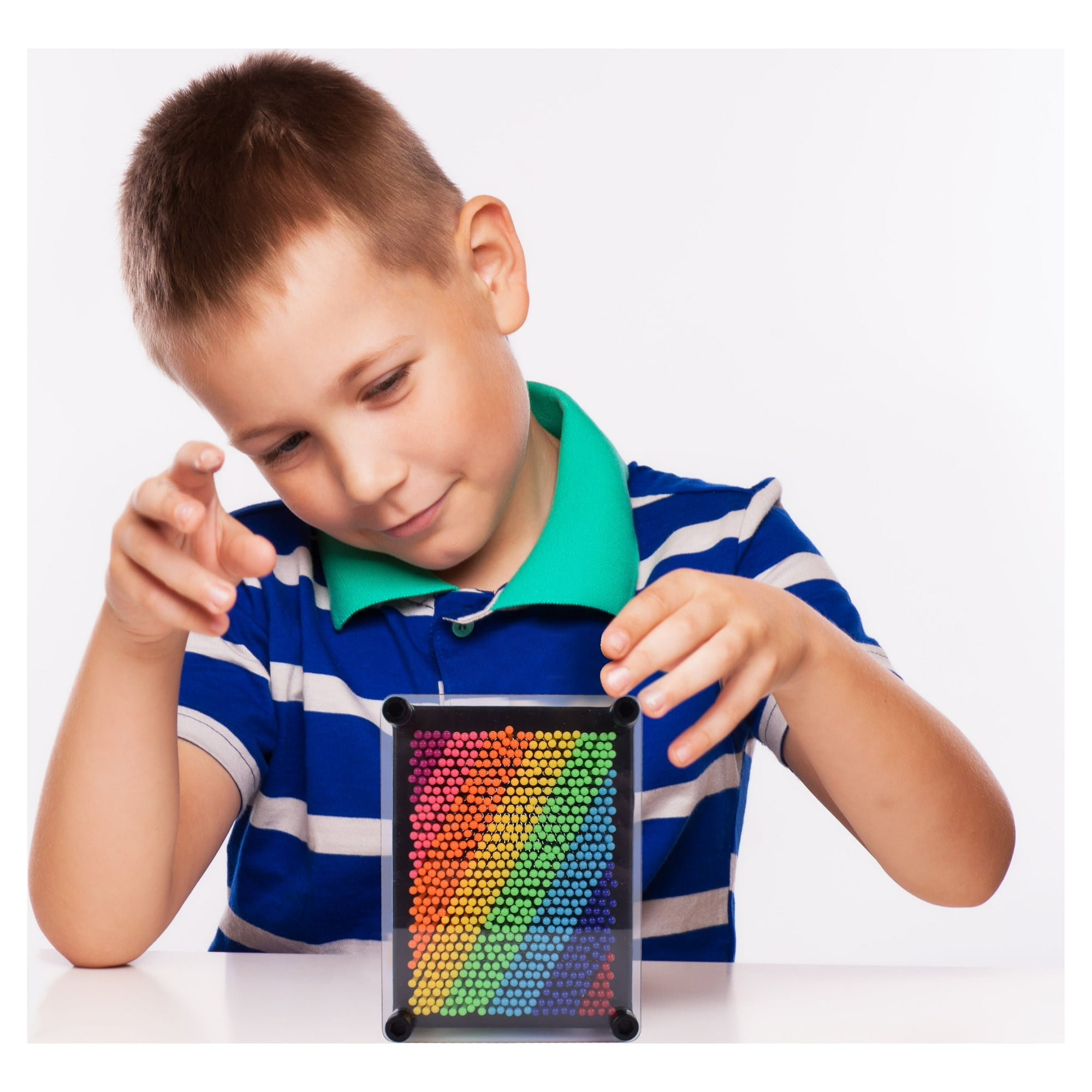Ein Junge in einem gestreiften Hemd betrachtet ein Regenbogen-Pin-Art-Spielzeug. Weißer Hintergrund.