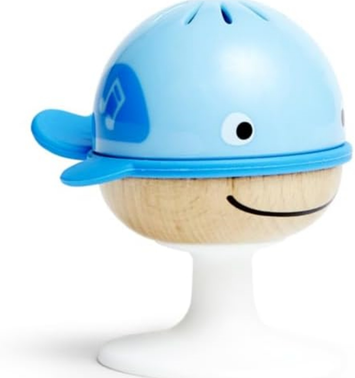 Ein walförmiges Spielzeug mit blauem Kopf, Holzkörper und weißem Sockel. Es hat ein lächelndes Gesicht und ein Notensymbol.