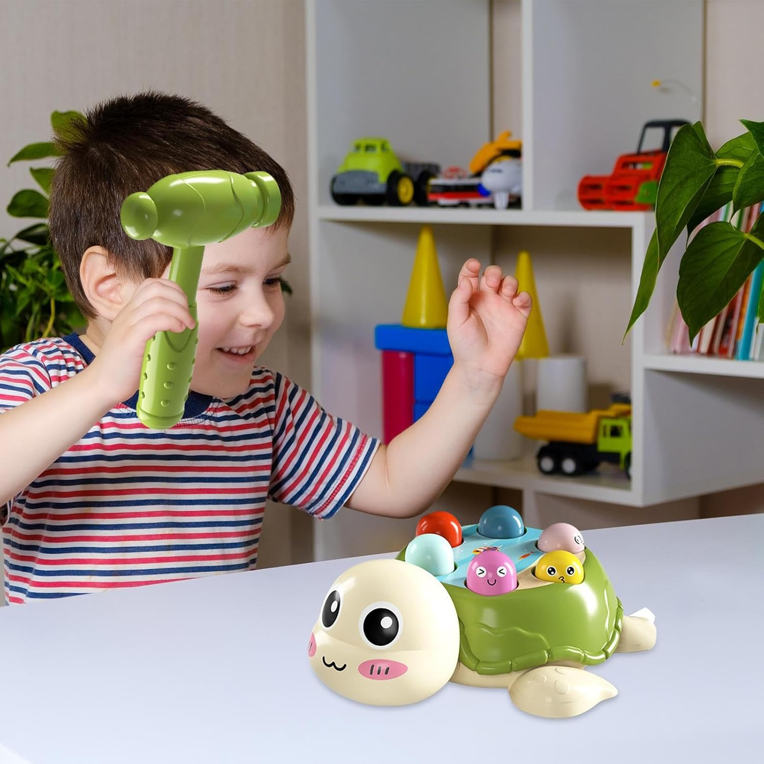 Ein Kind spielt mit einem Spielzeughammer und einem schildkrötenförmigen Spielzeug mit bunten Kugeln. Regale mit Spielzeug sind im Hintergrund.