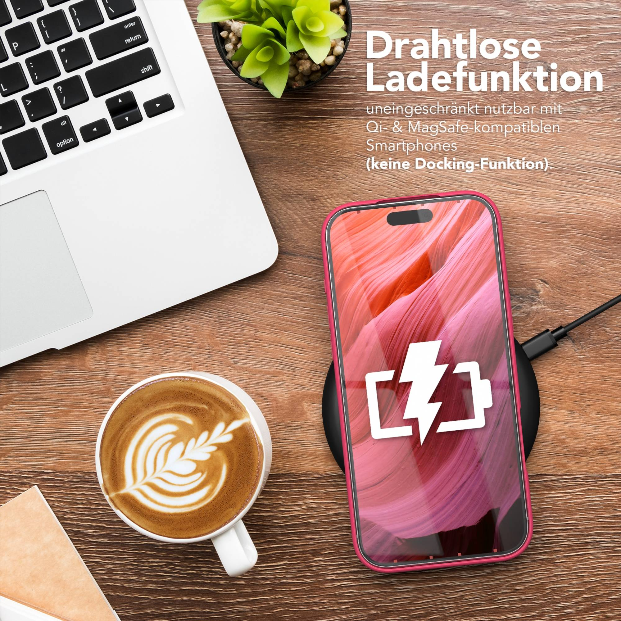 Ein Telefon, das auf einem kabellosen Ladegerät geladen wird, neben einem Laptop und einer Kaffeetasse mit Latte Art.