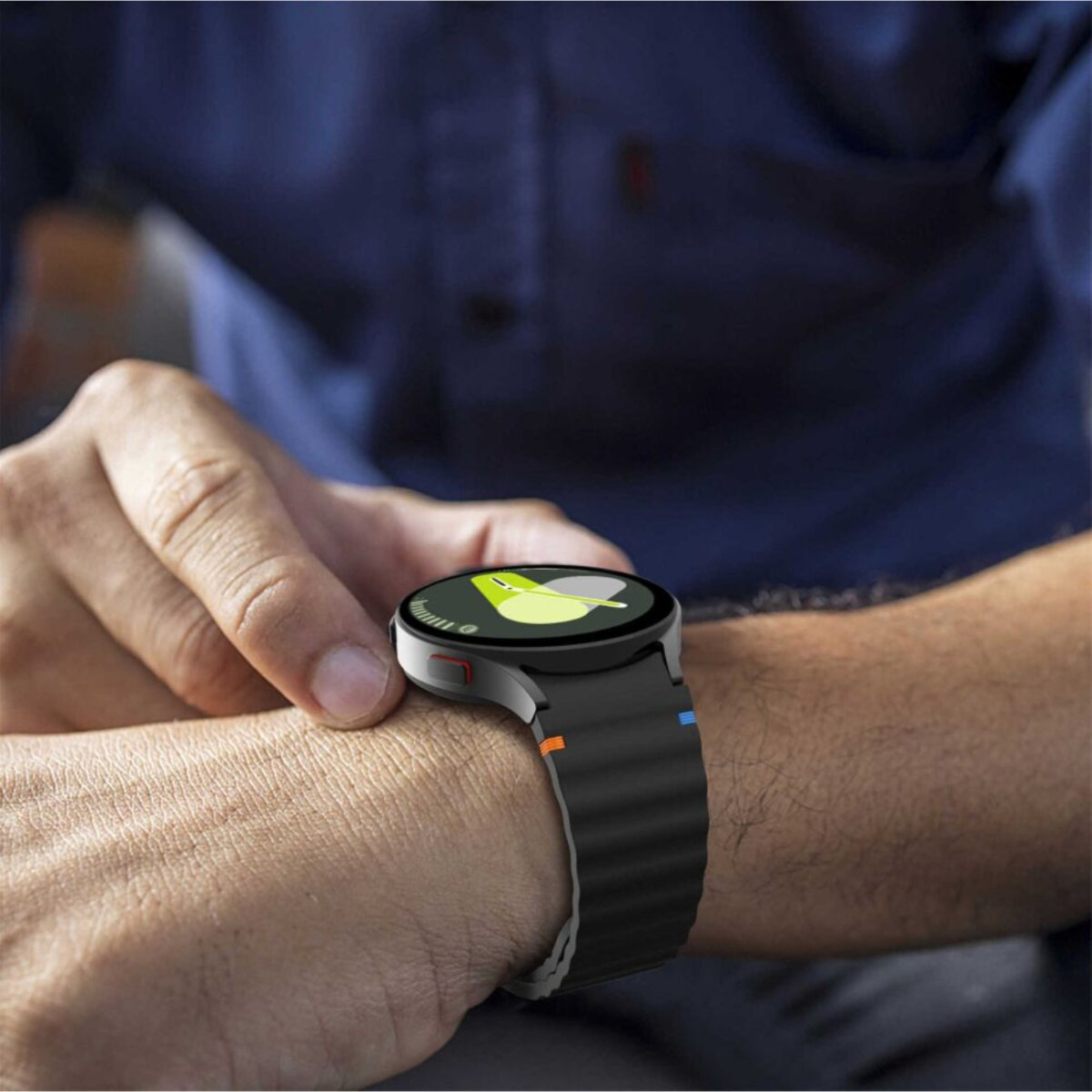 Une personne porte une smartwatch avec un bracelet noir. Le cadran affiche un design vert et jaune. La personne touche la montre.