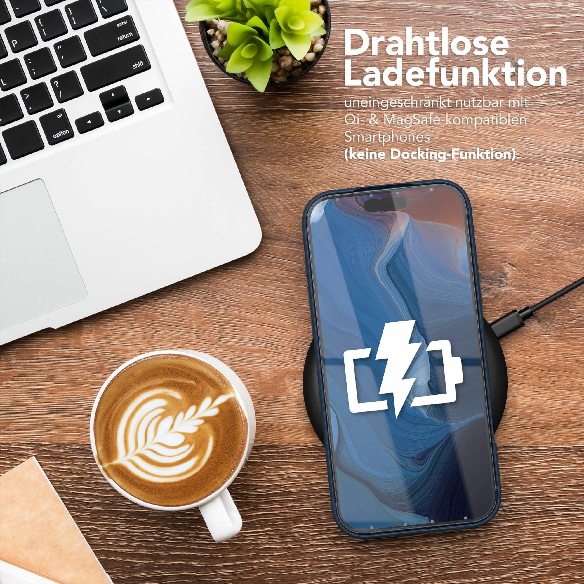 Ein Telefon, das auf einem kabellosen Ladegerät geladen wird, neben einem Laptop und einer Kaffeetasse mit Latte Art.