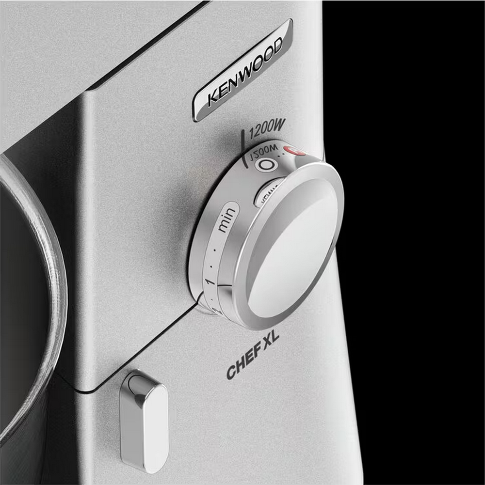Zbliżenie srebrnego miksera Kenwood Chef XL. Widoczne pokrętło prędkości i przycisk zasilania. Tło jest czarne.