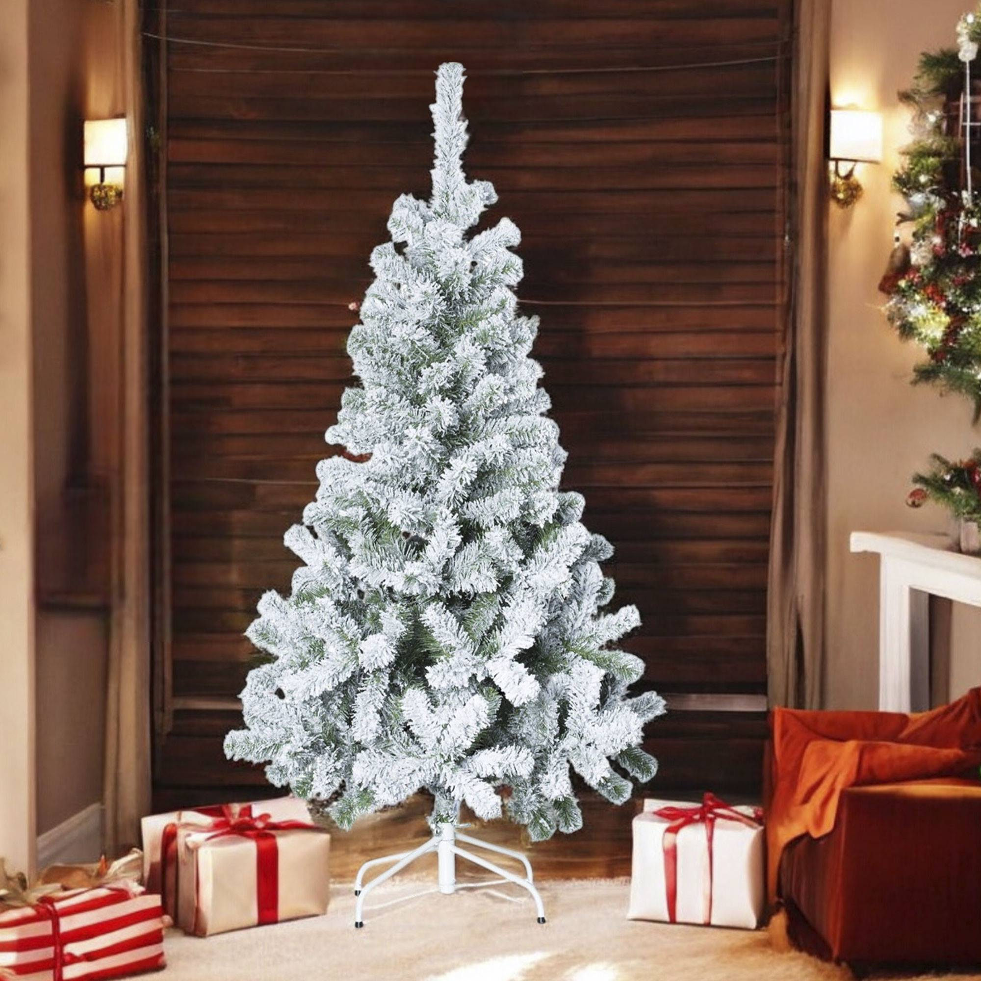 Un árbol de Navidad nevado se alza frente a paneles de madera. Regalos con cintas rojas rodean el árbol.