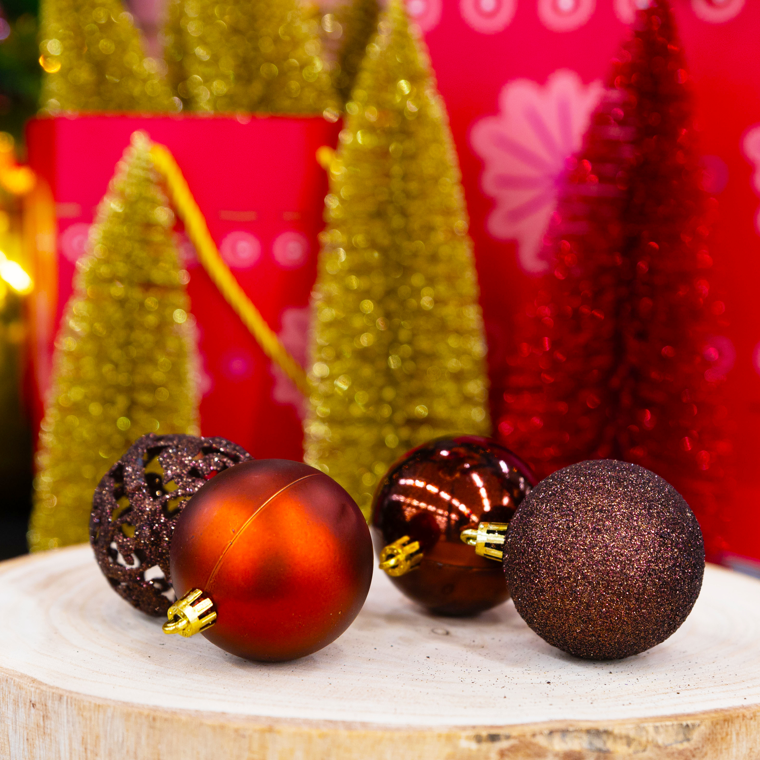 Ornements de Noël sur bois. Boules marron et rouges avec des accents dorés, et sapins dorés et rouges en arrière-plan.